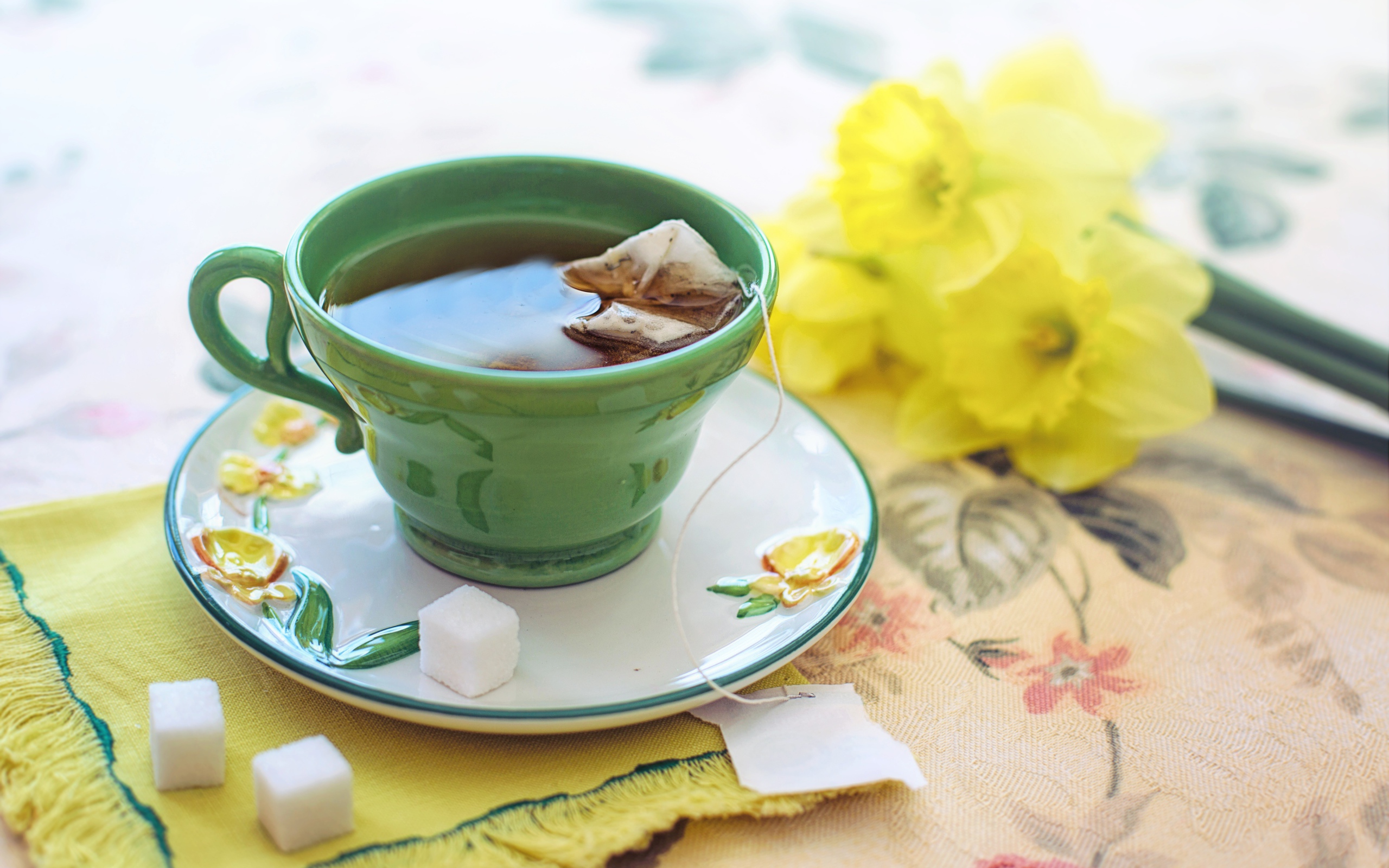 Чашка чая на столе с сахаром и нарциссами