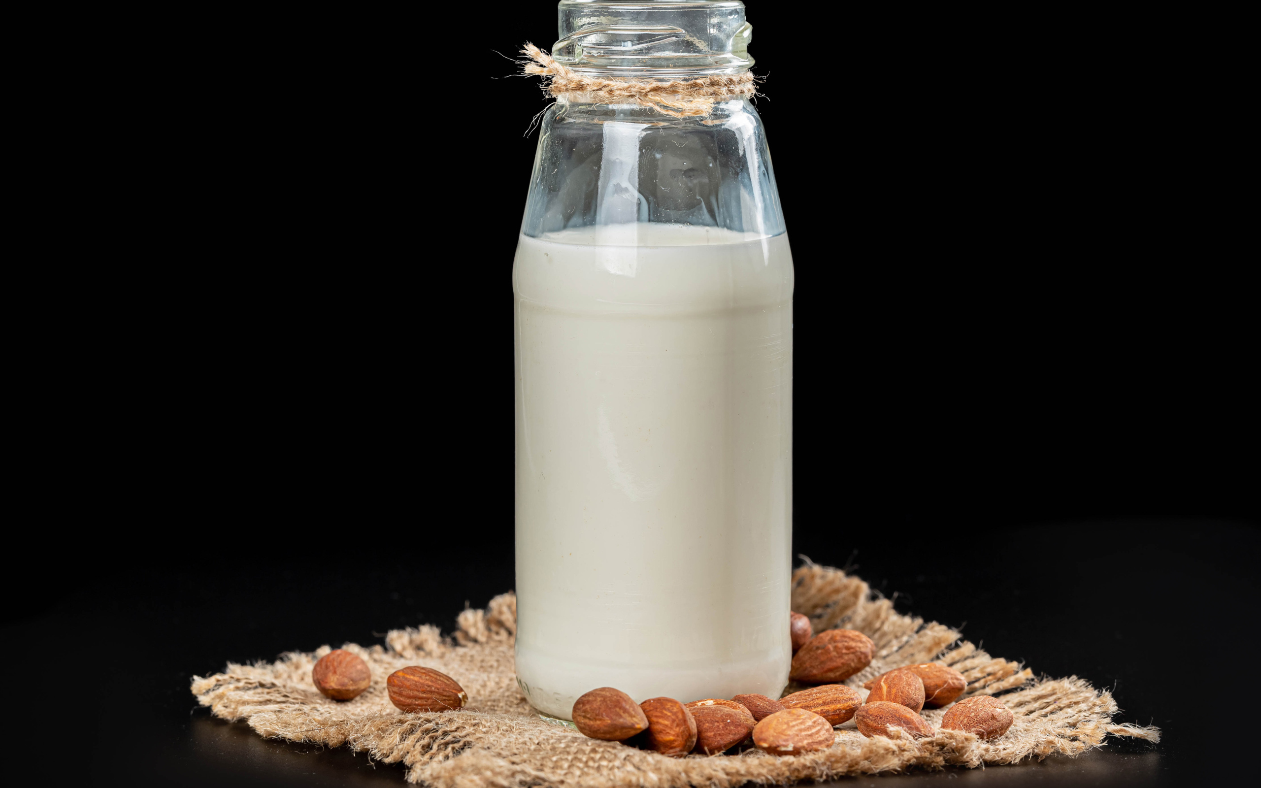 Молоко с миндалем на черном фоне