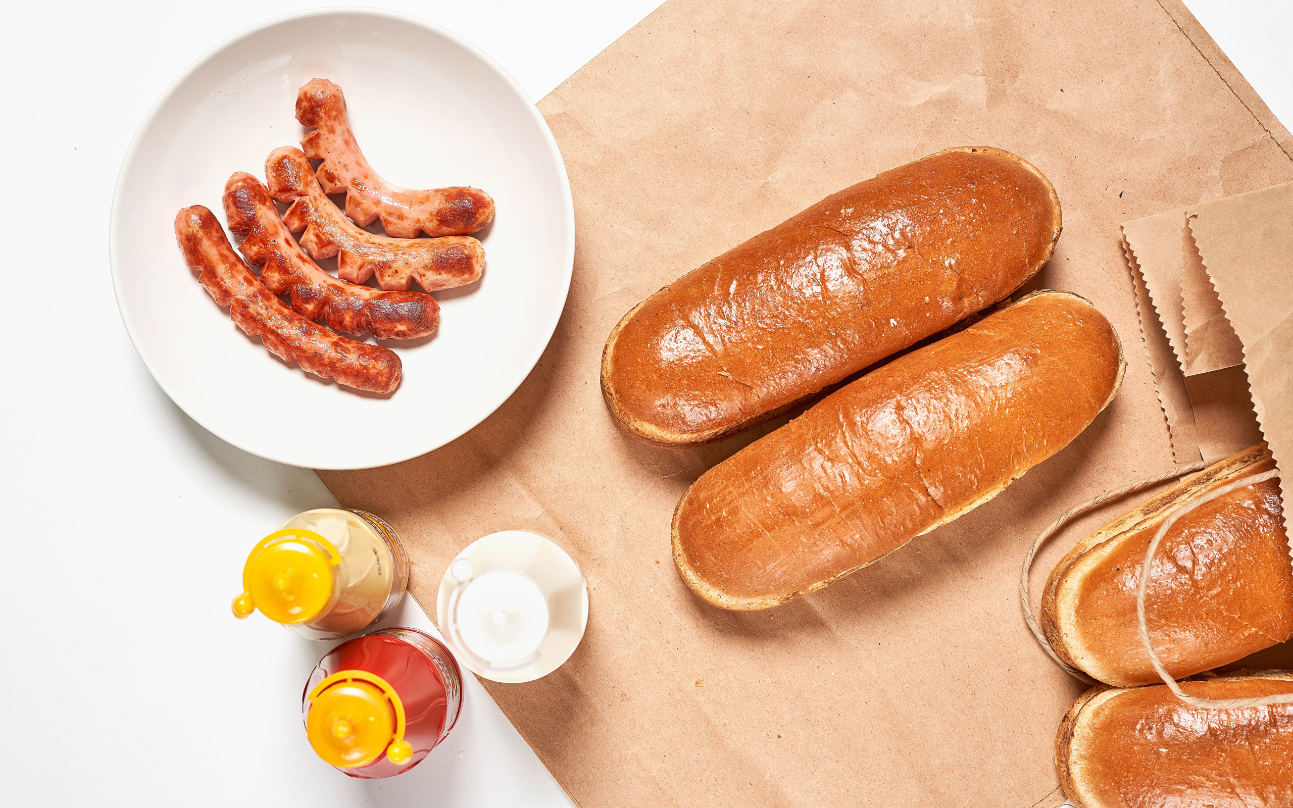 Булки для хот дога с сосисками на столе с соусом