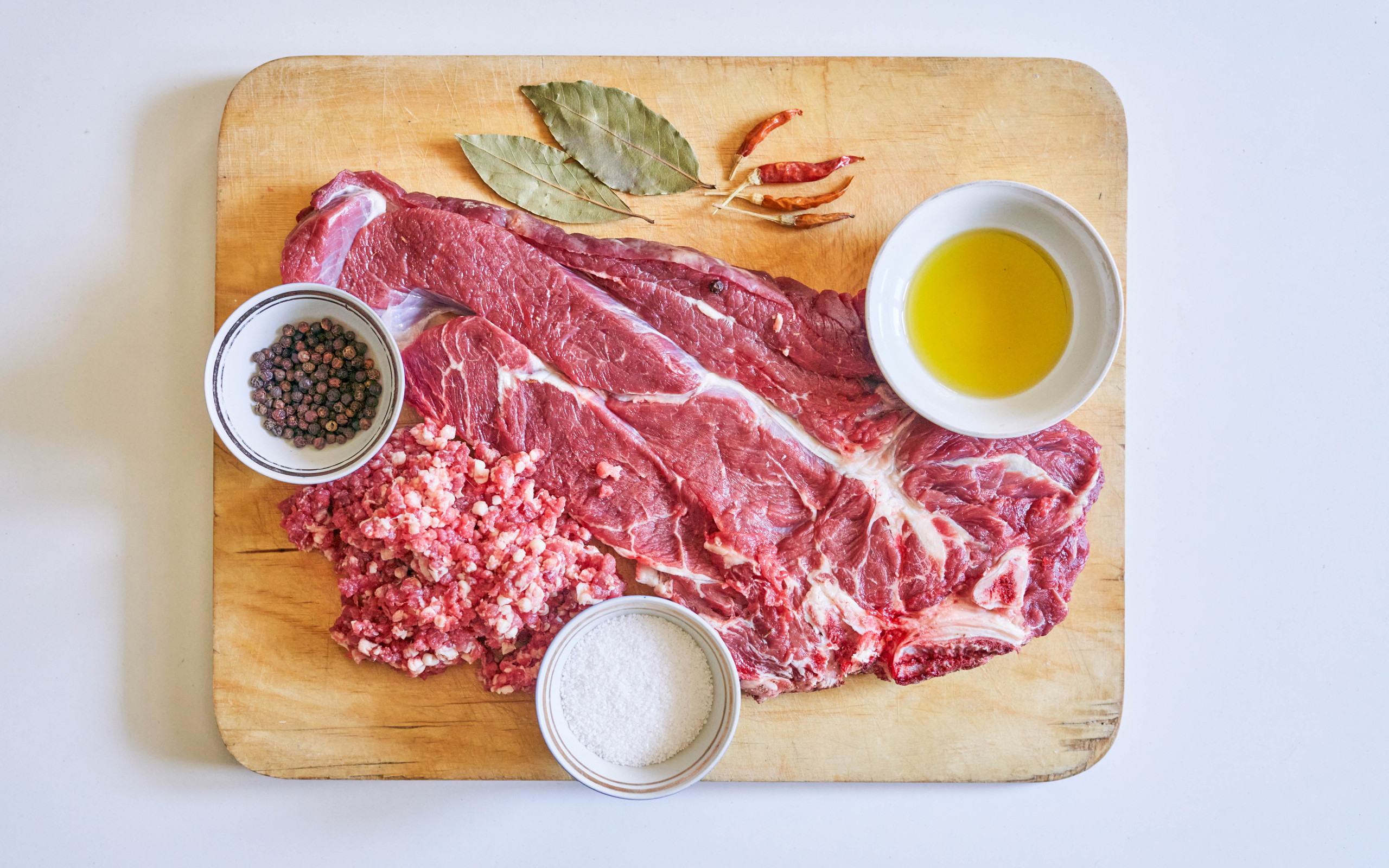 Кусок мяса со специями и оливковым маслом на доске 