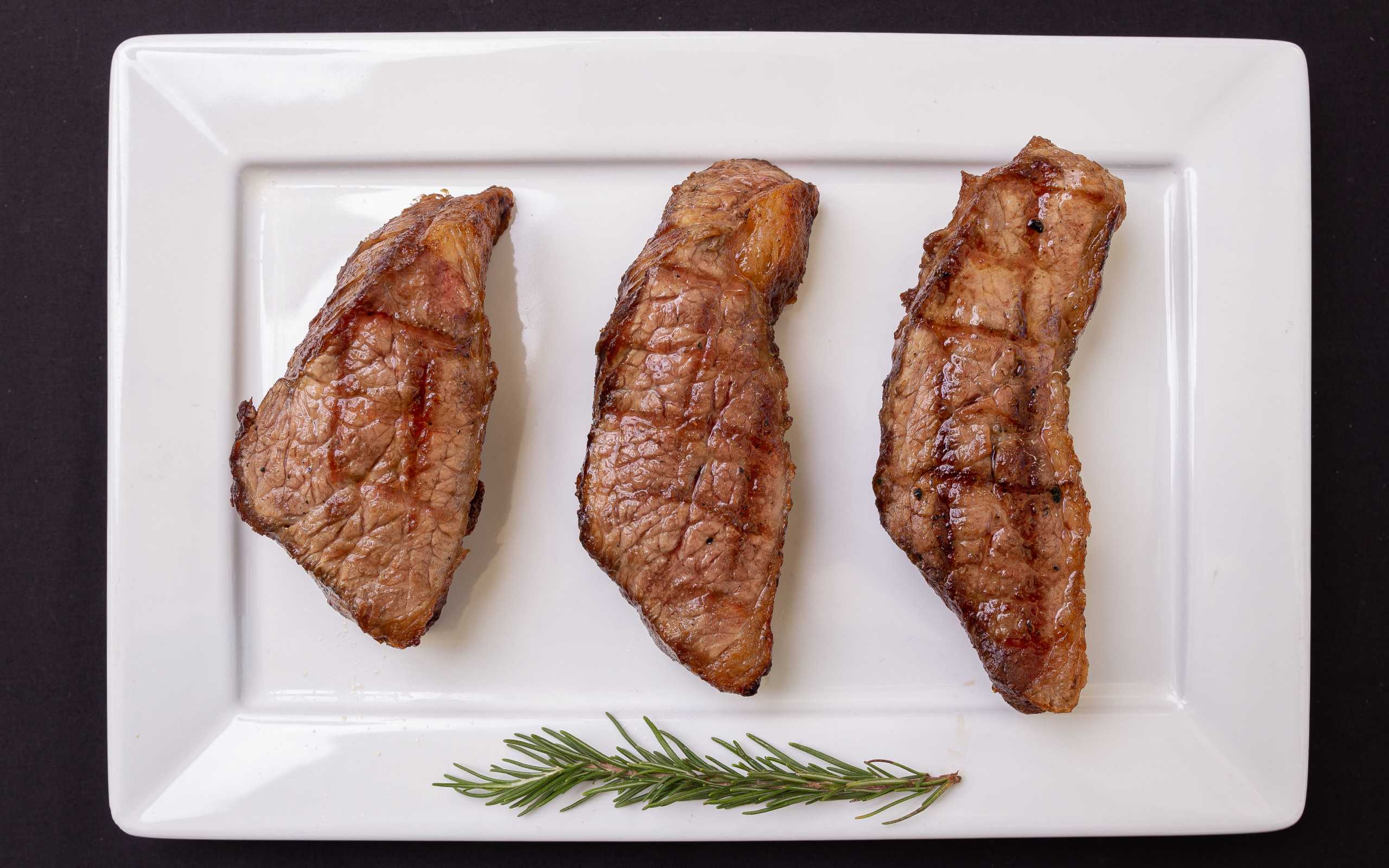 Три куска жареного мяса на большой белой тарелке