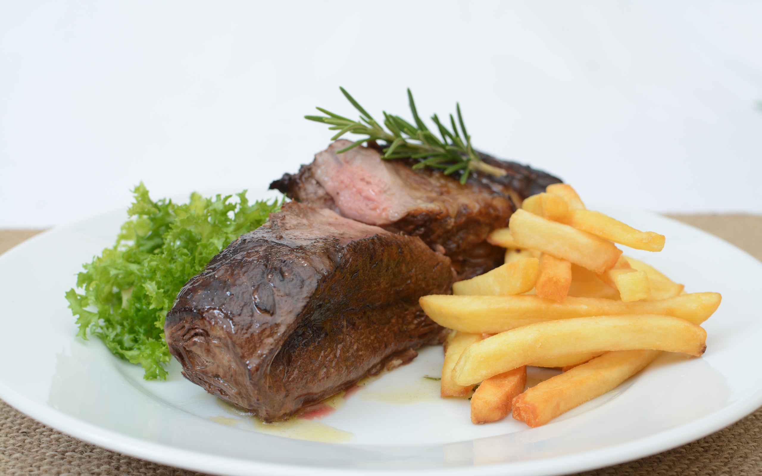 Два куска мяса на тарелке с картофелем фри 