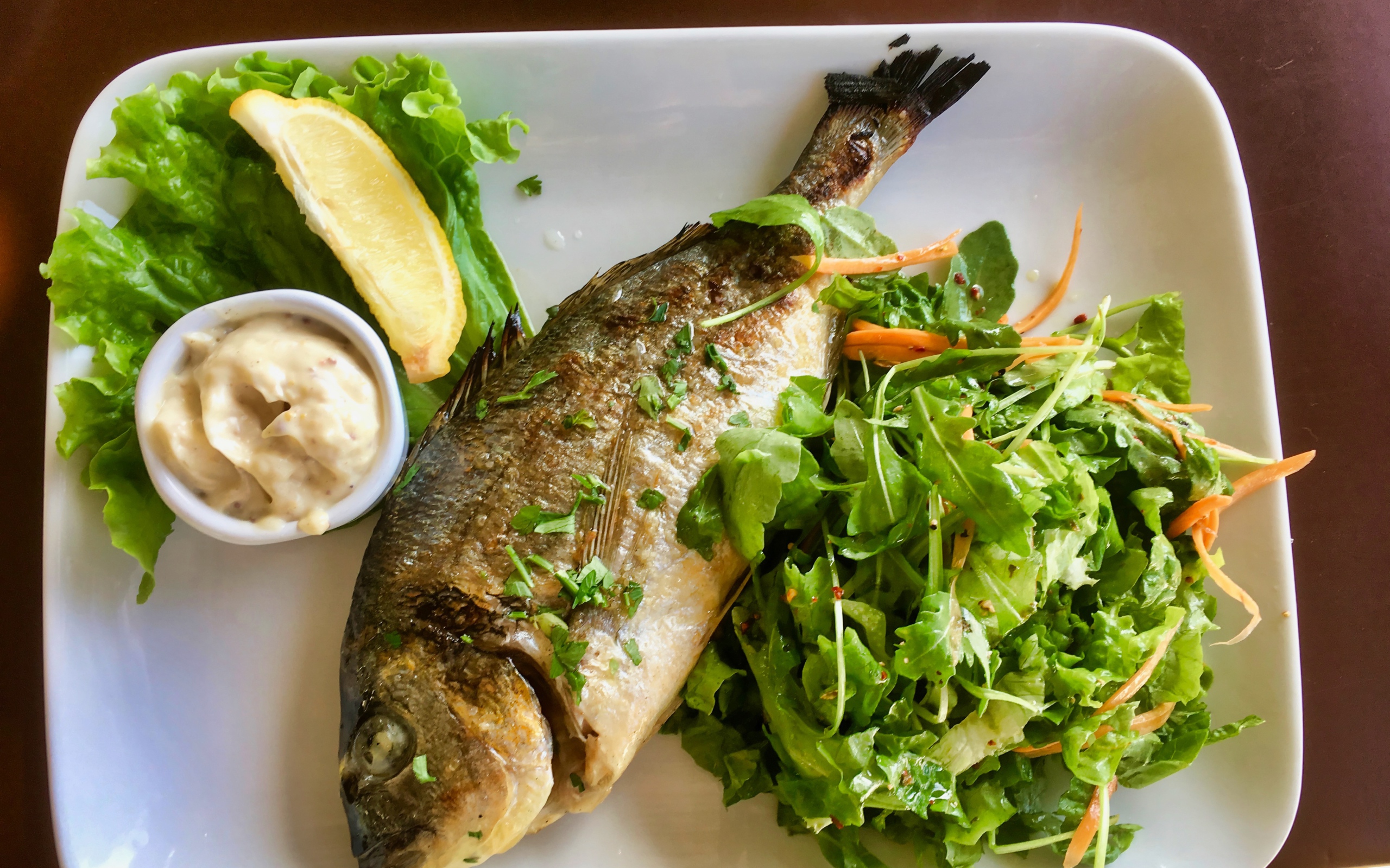 Жареный карась на тарелке с салатом 