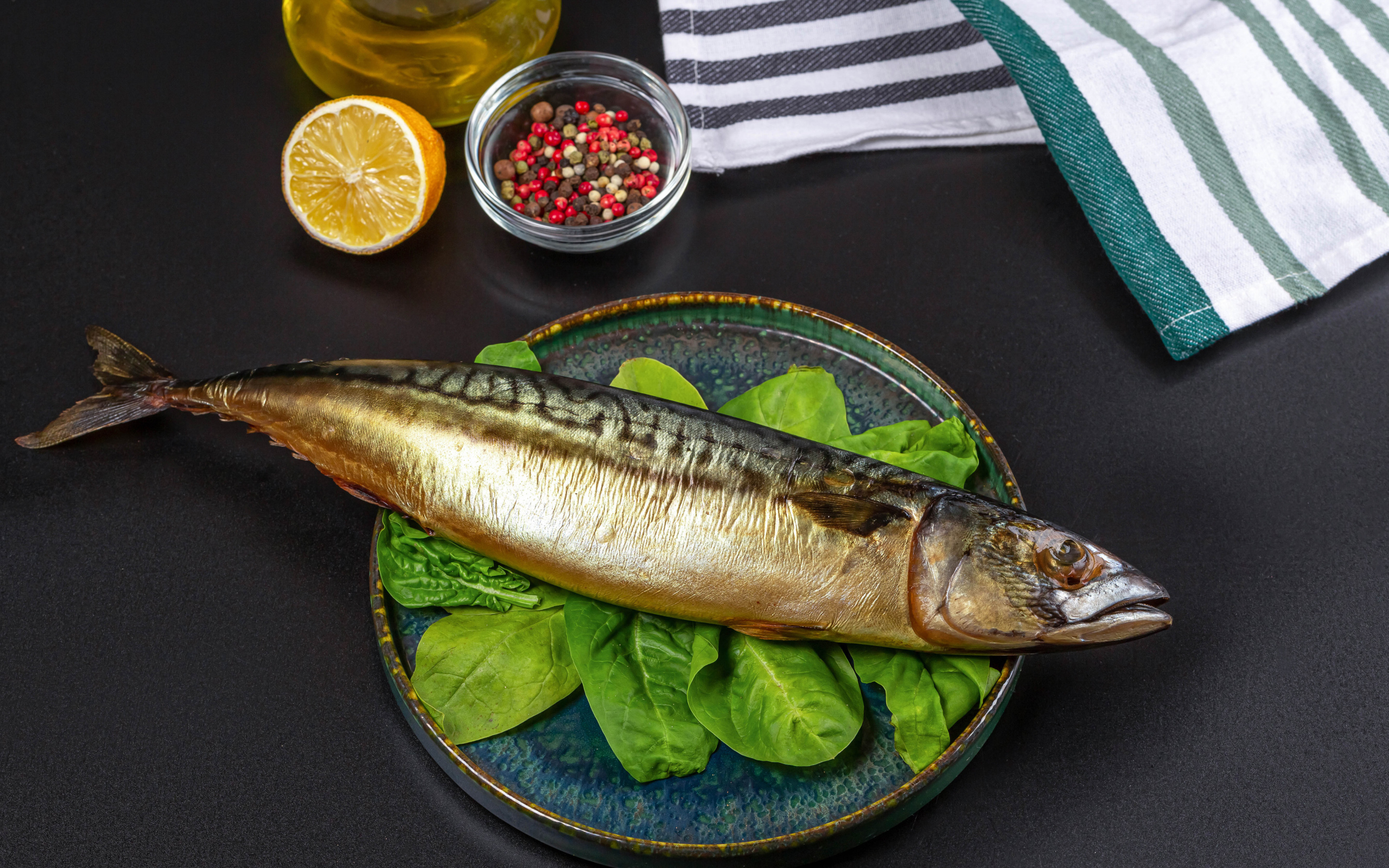 Большая копченая скумбрия на тарелке с базиликом