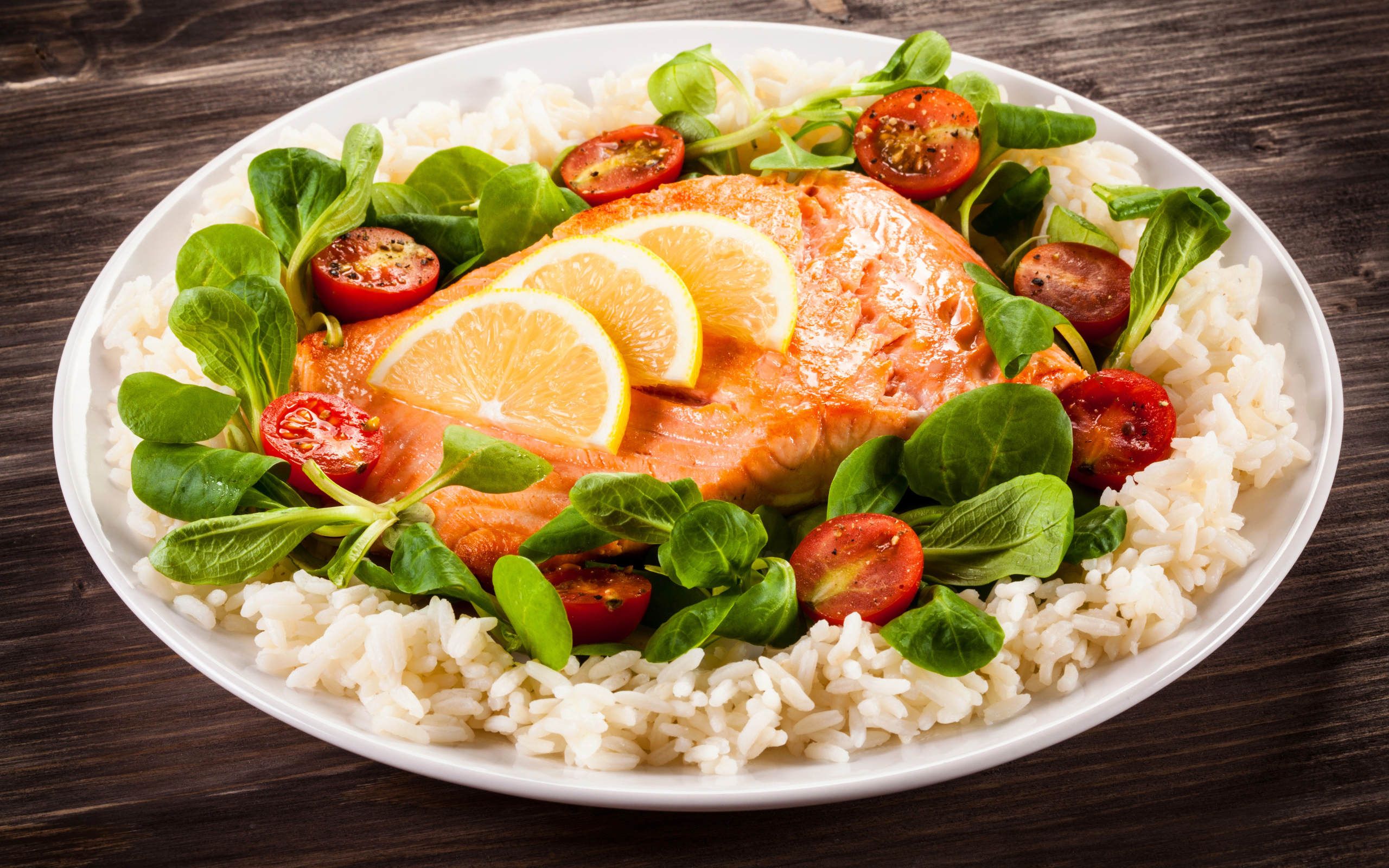 Кусок рыбы на тарелке с помидорами, рисом и листьями базилика 