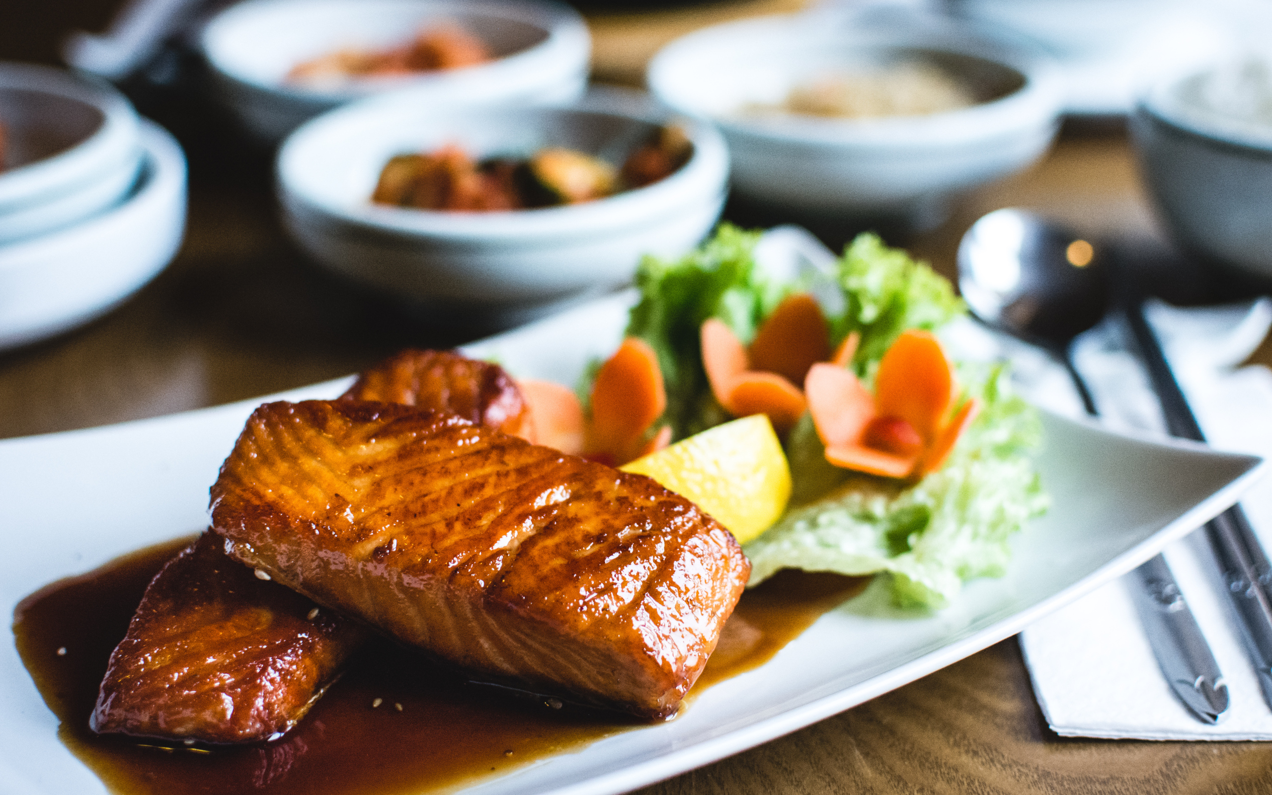 Два куска рыбы в соусе с овощами на тарелке