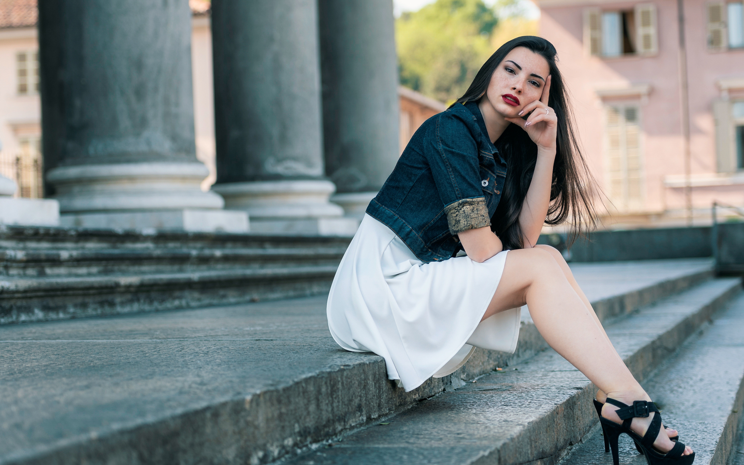 Девушка в белом платье сидит на ступеньках