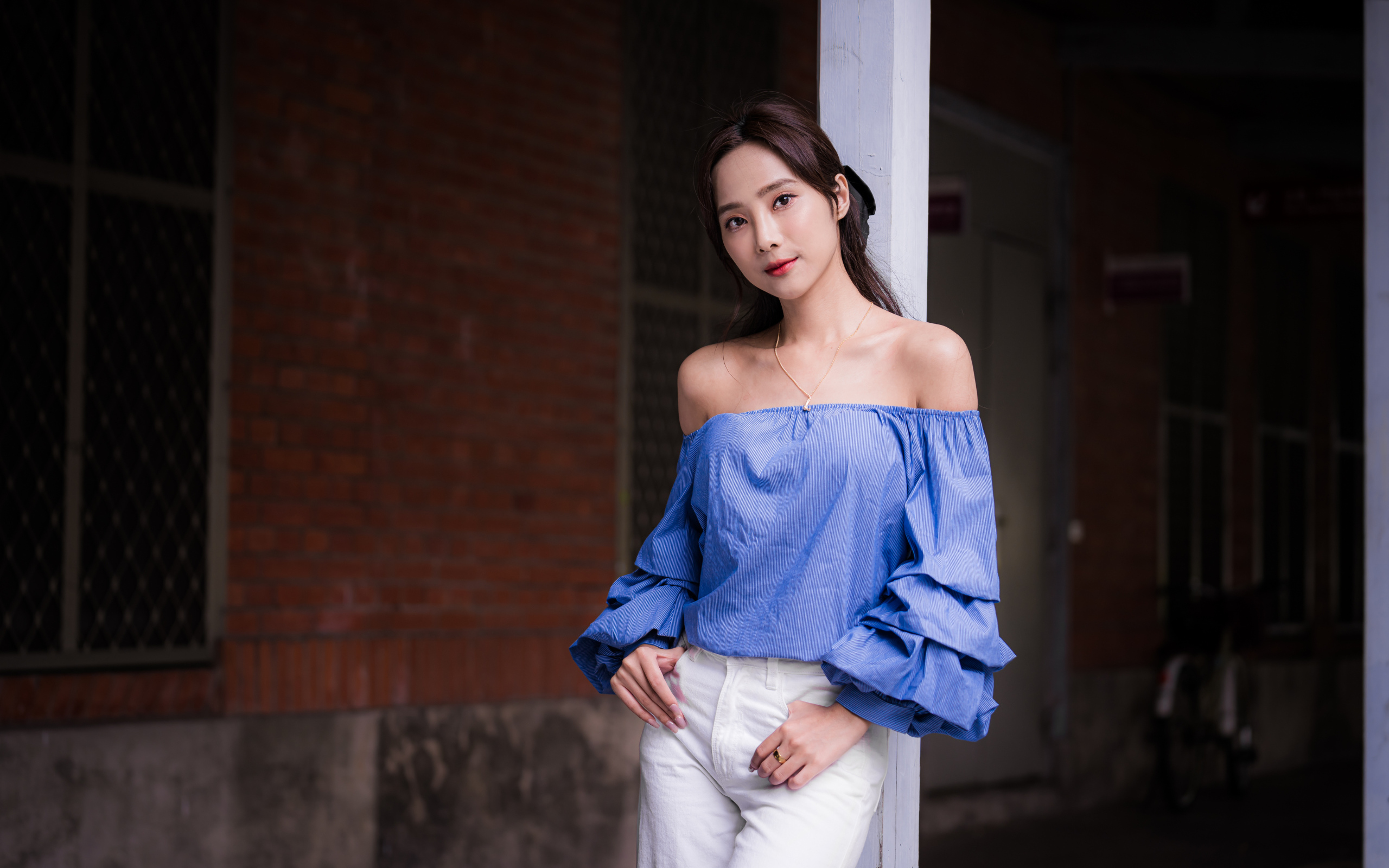 Девушка азиатка в белых брюках у дома