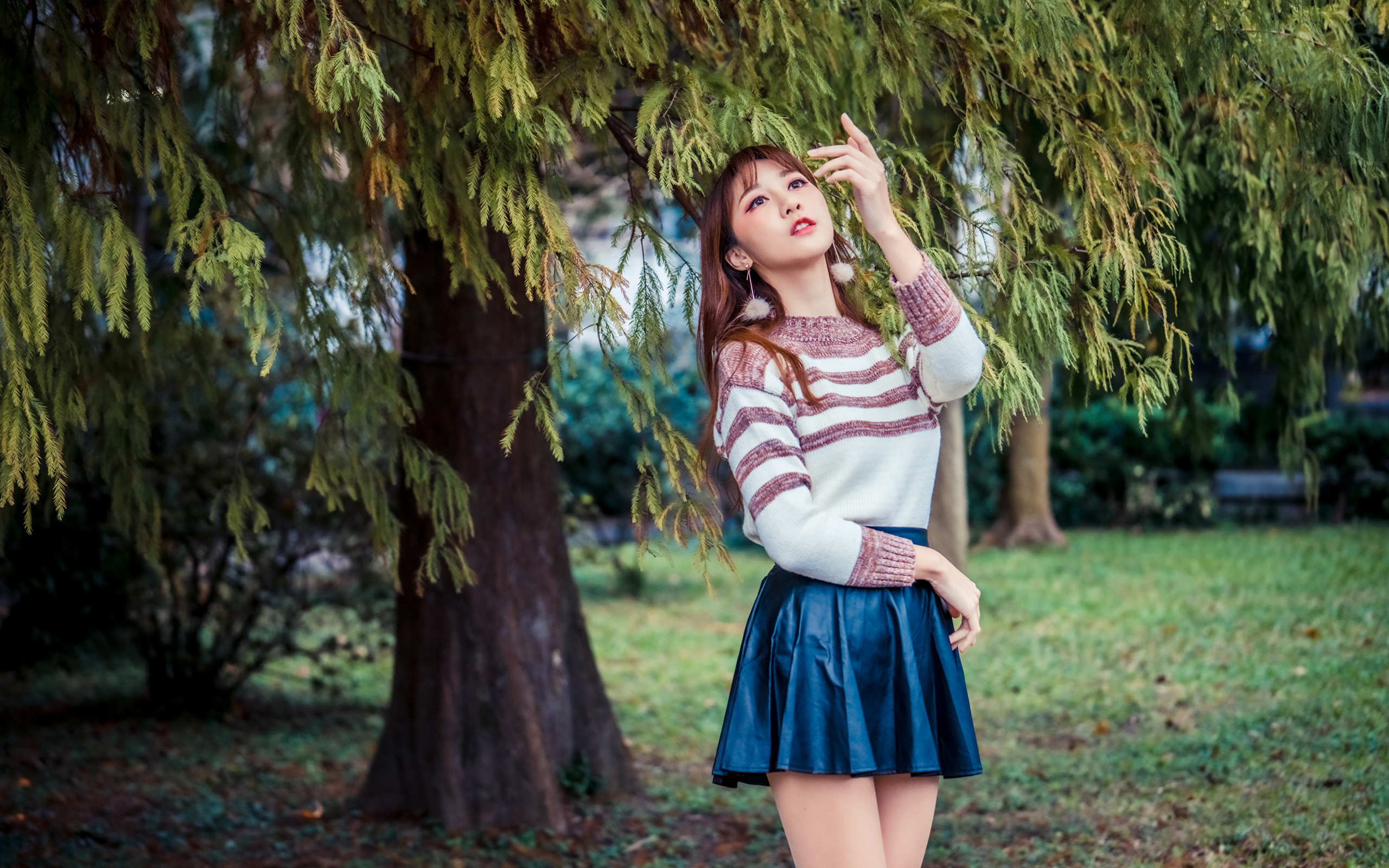 Красивая девушка азиатка стоит у дерева в парке