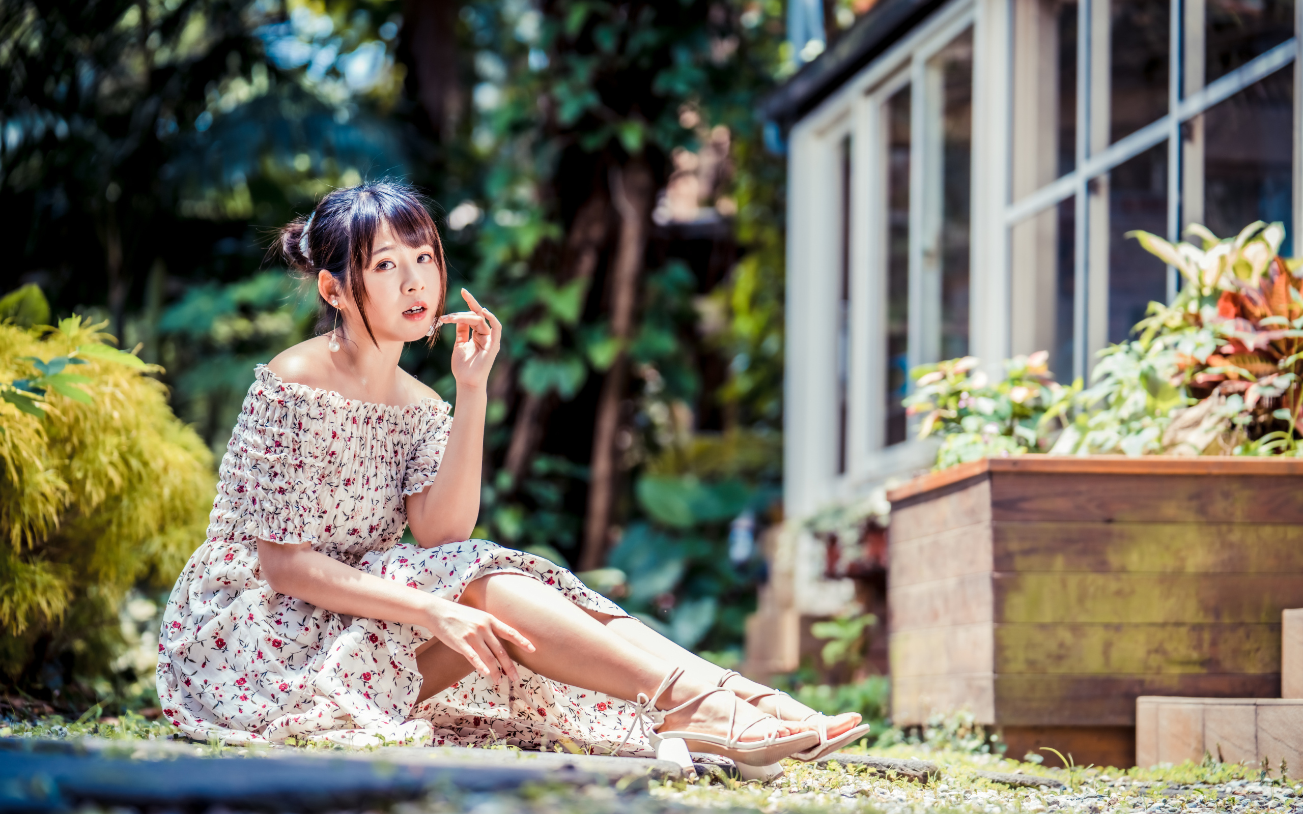 Красивая девушка азиатка в платье сидит на земле