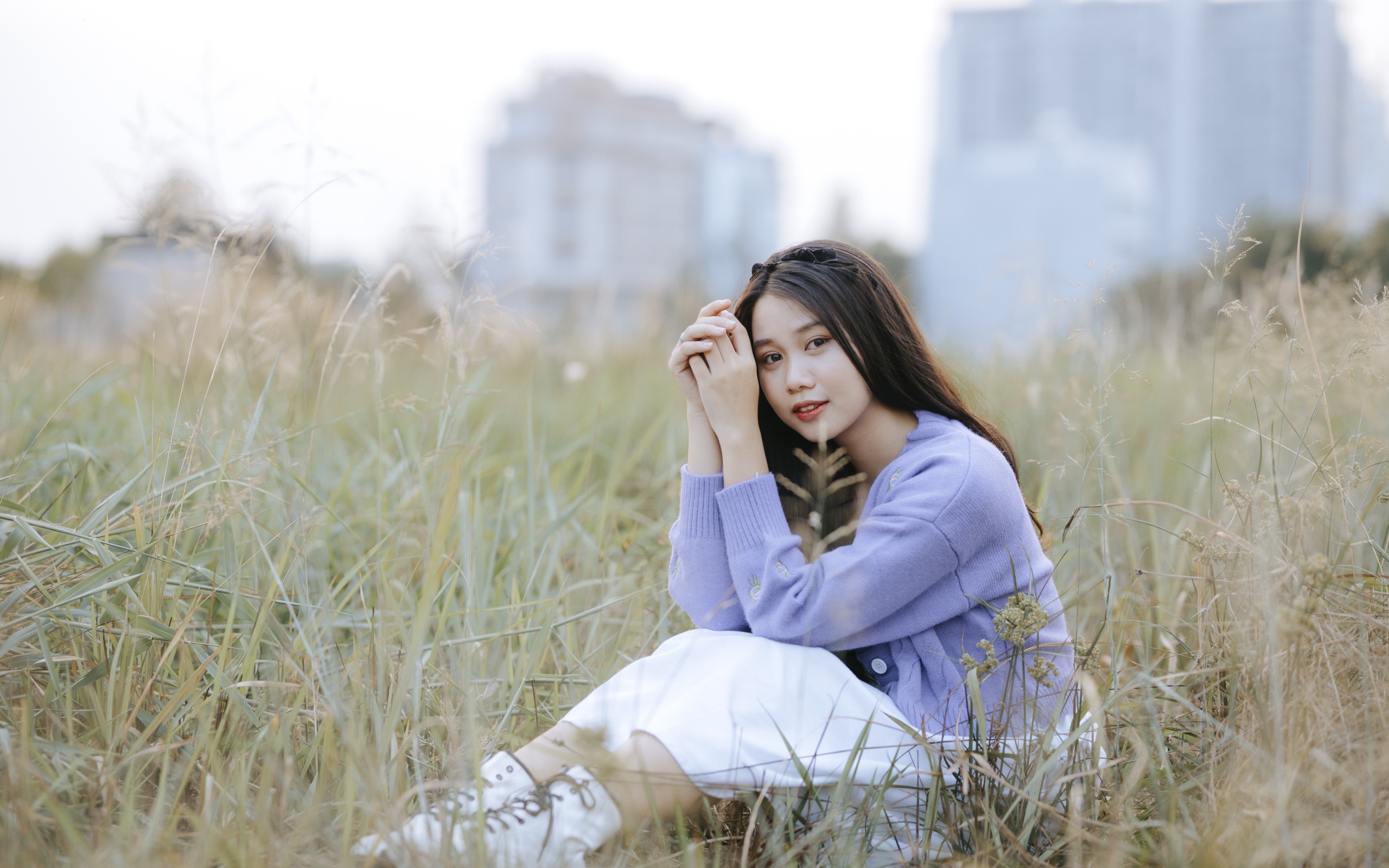 Красивая девушка азиатка сидит на поле с травой 