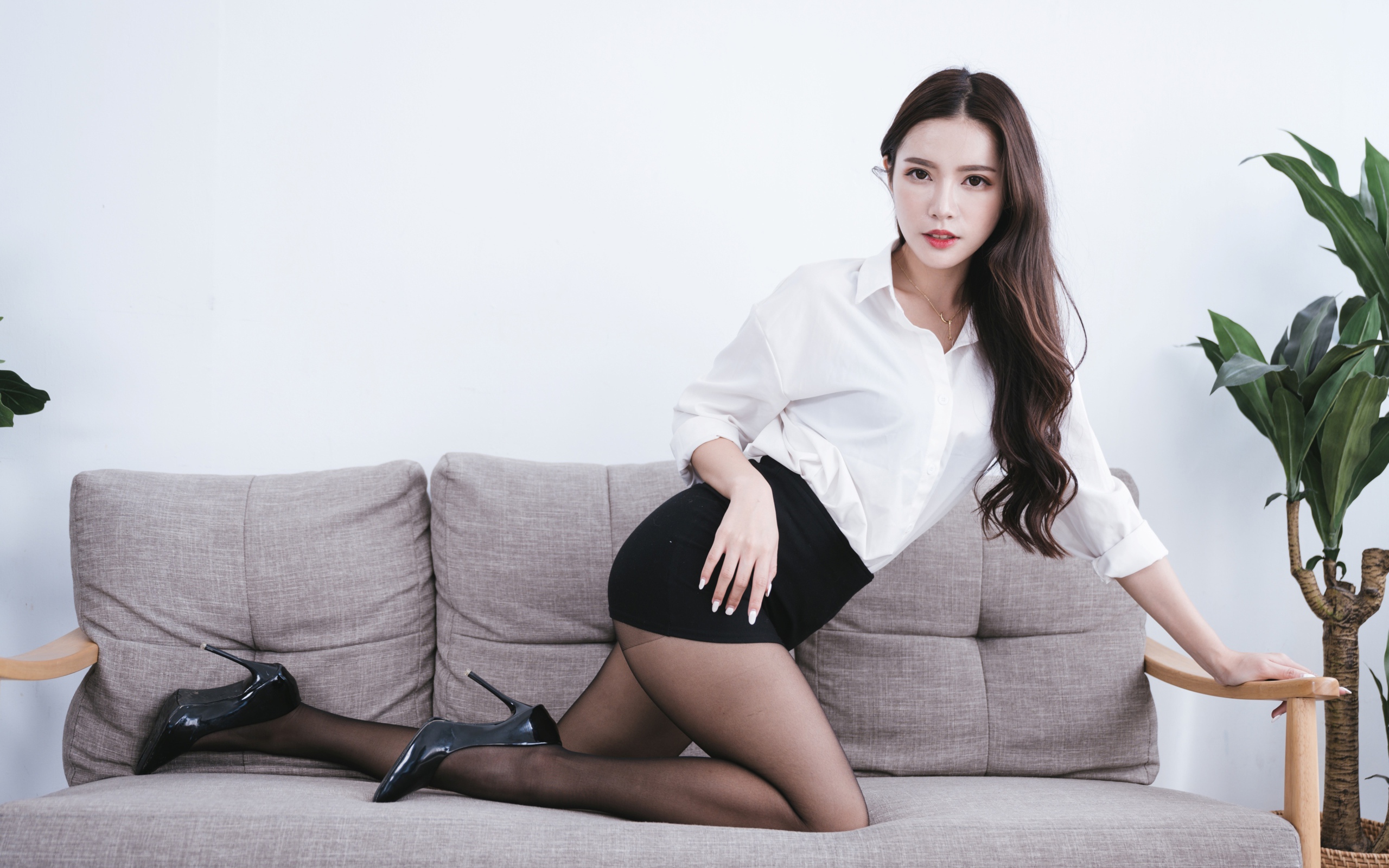 Красивая азиатка в белой рубашке на диване