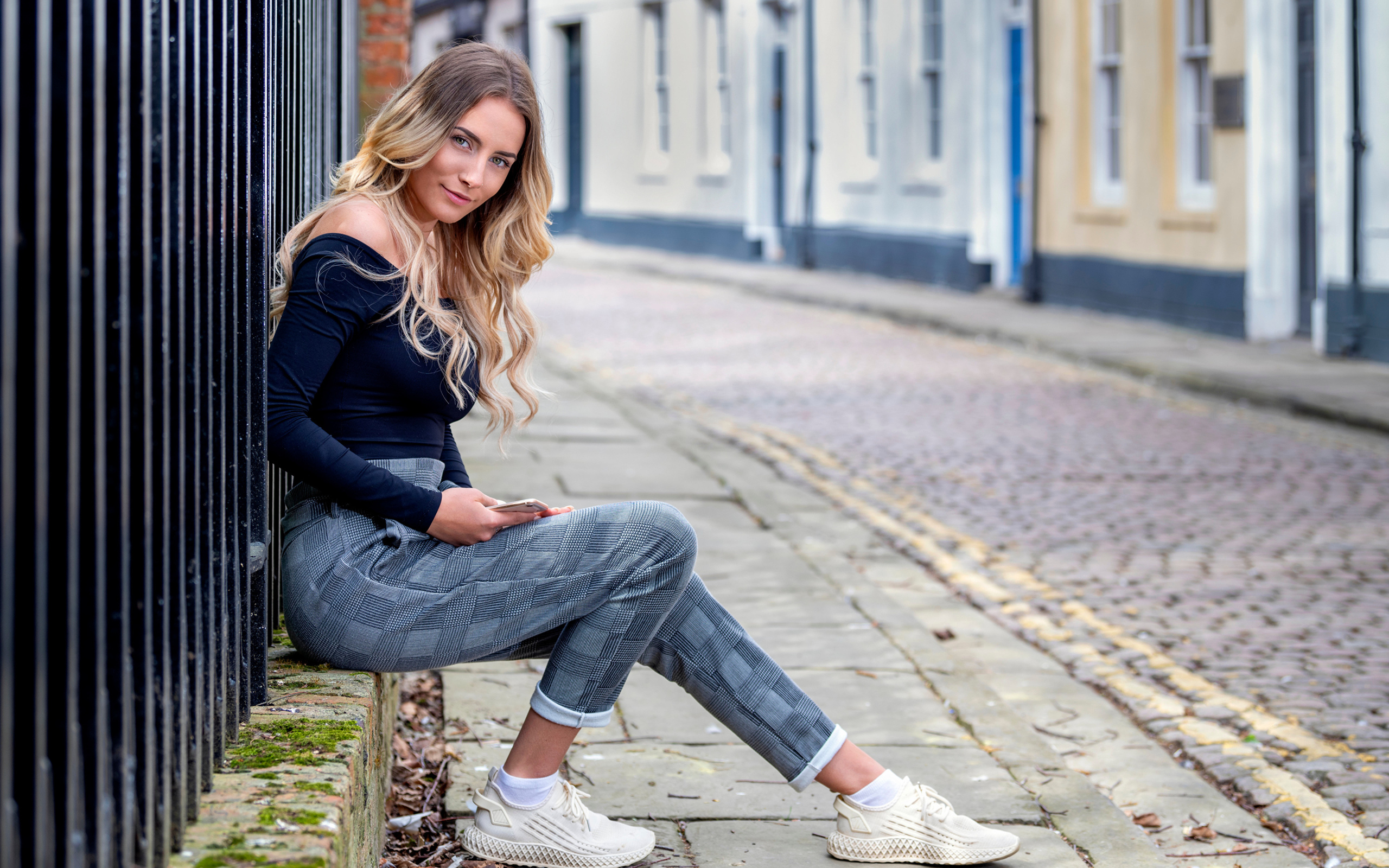 Красивая девушка блондинка сидит у забора