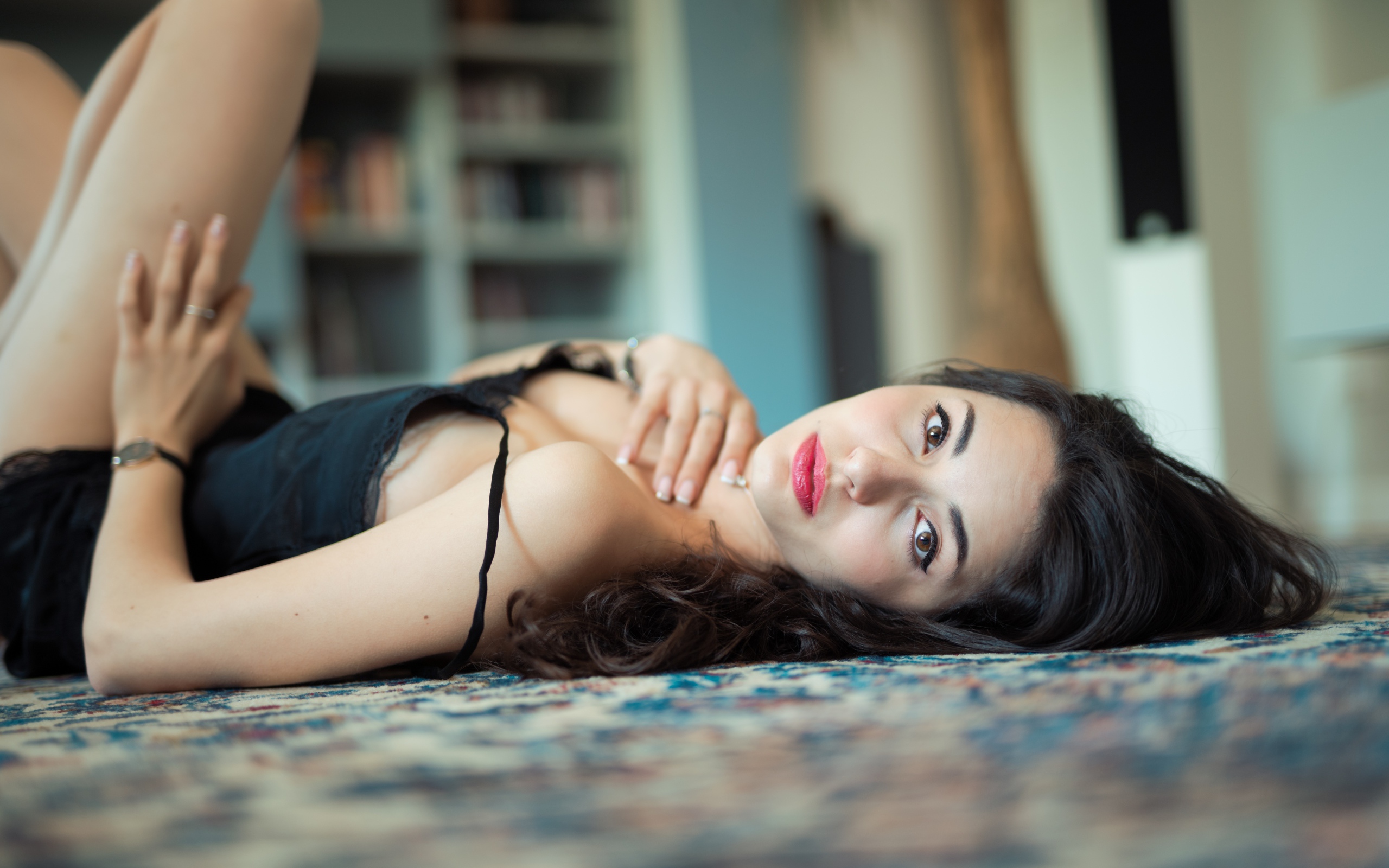 Красивая брюнетка в черном платье лежит на полу