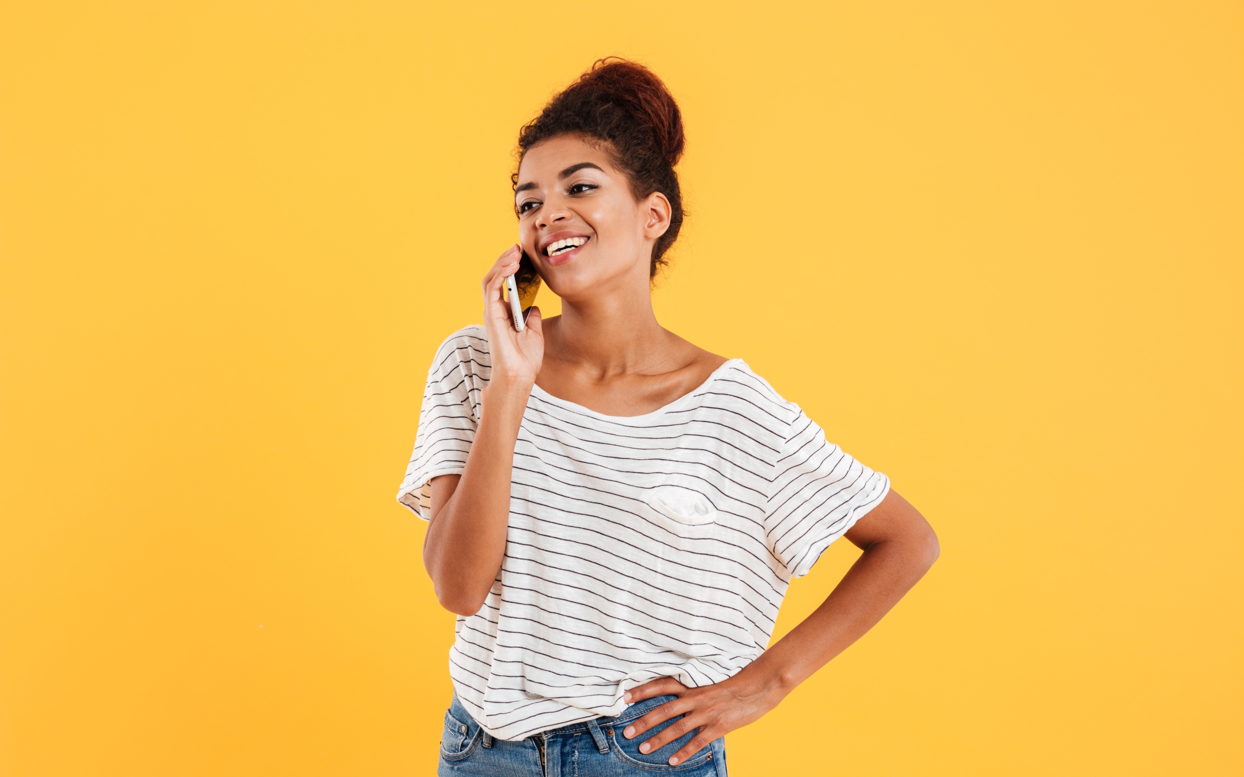 Красивая девушка со смартфоном на желтом фоне