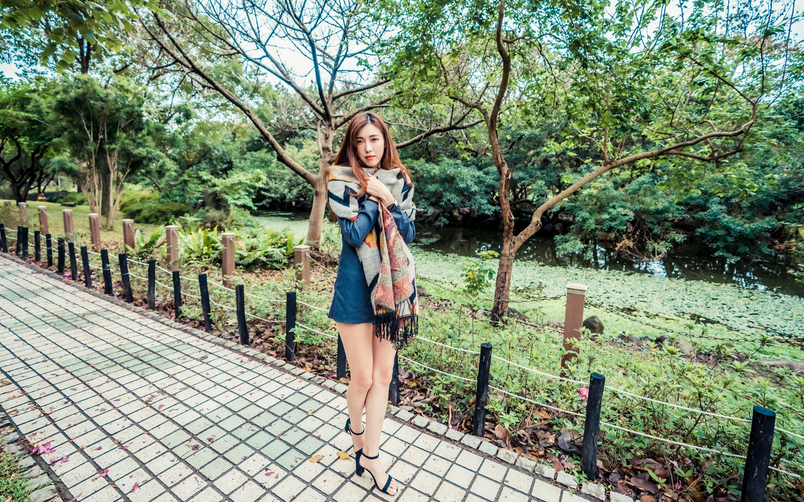 Милая девушка азиатка стоит в осеннем парке 