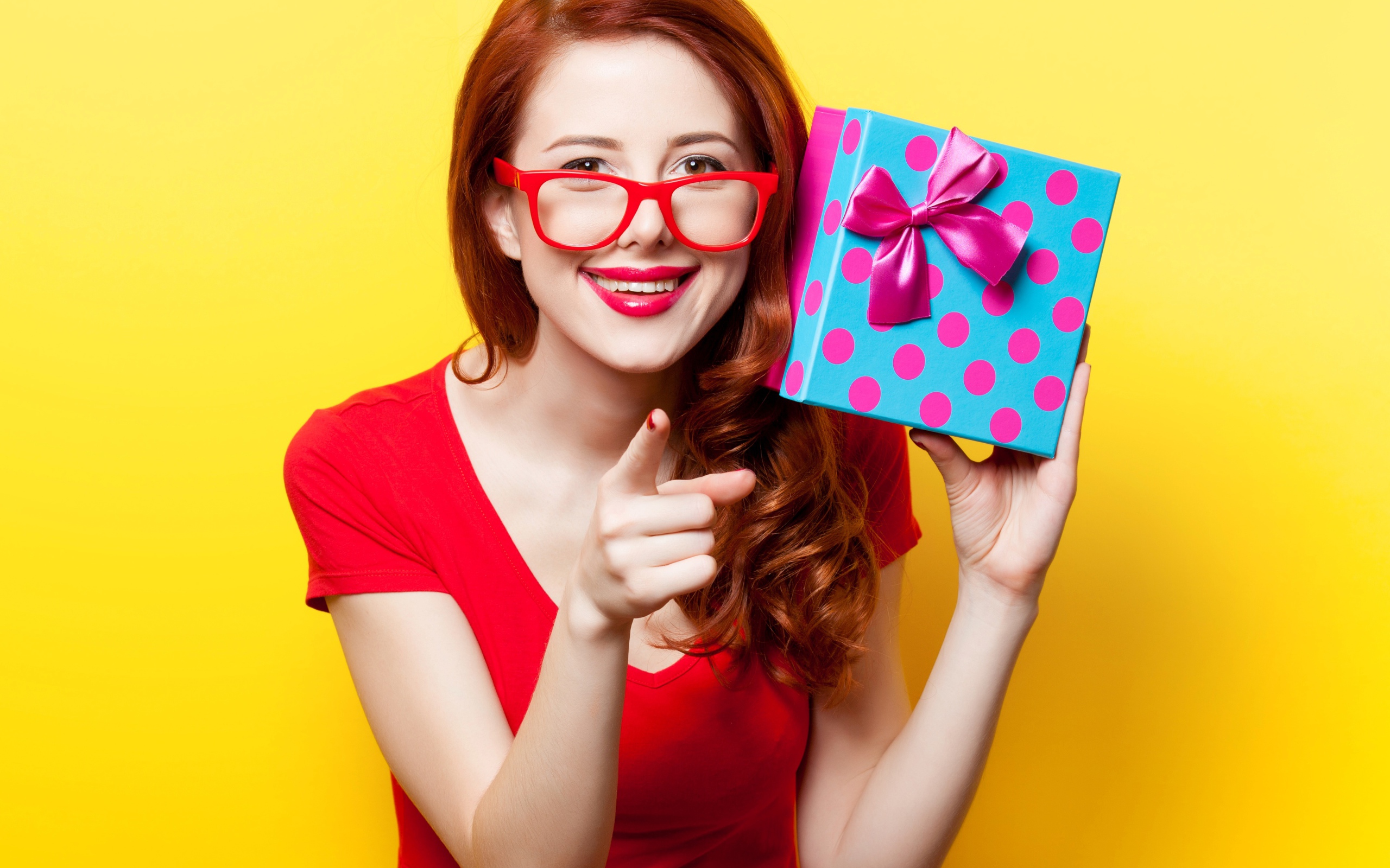 Девушка в очках с подарком в руке на желтом фоне