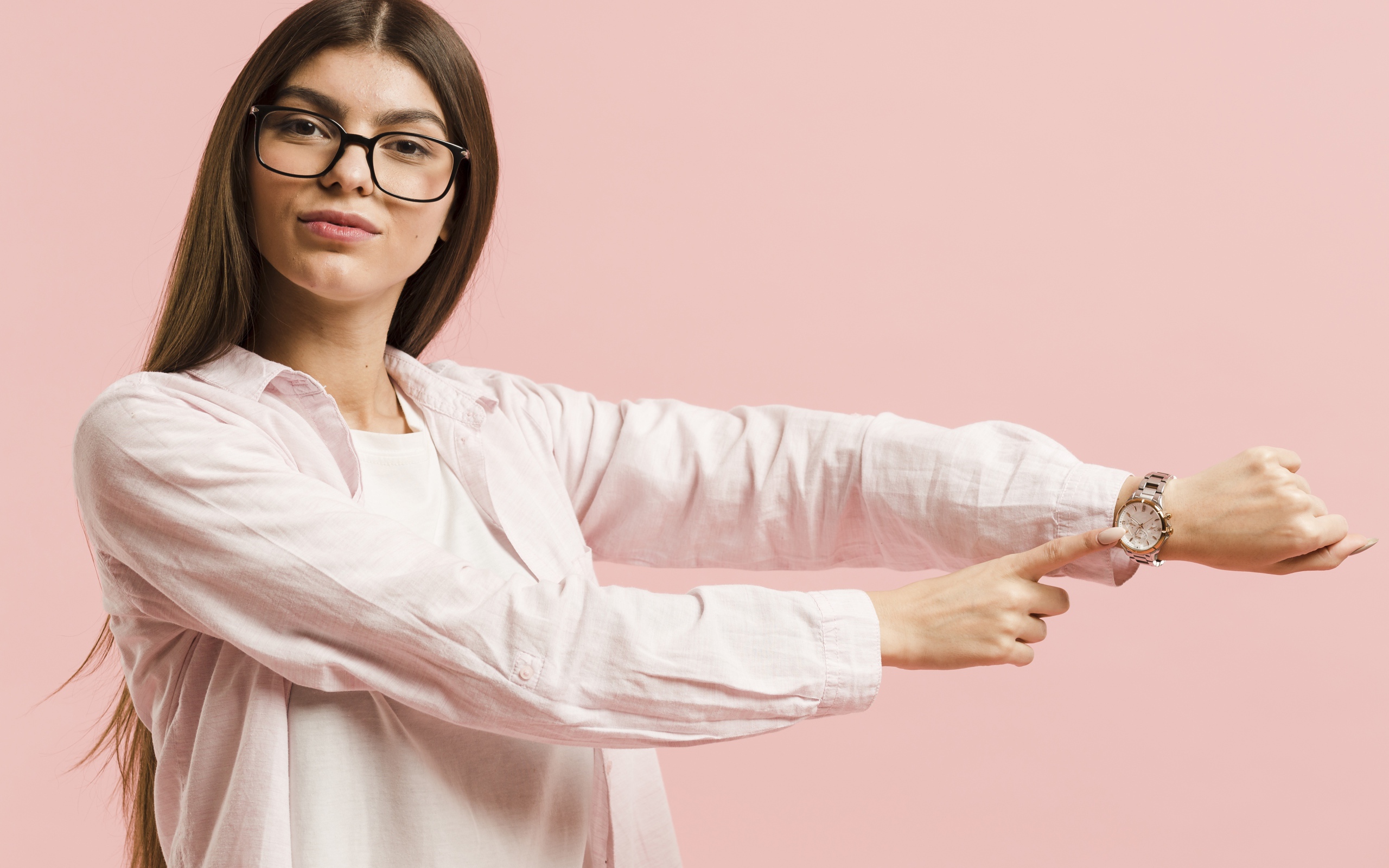 Девушка с часами на руке на розовом фоне 