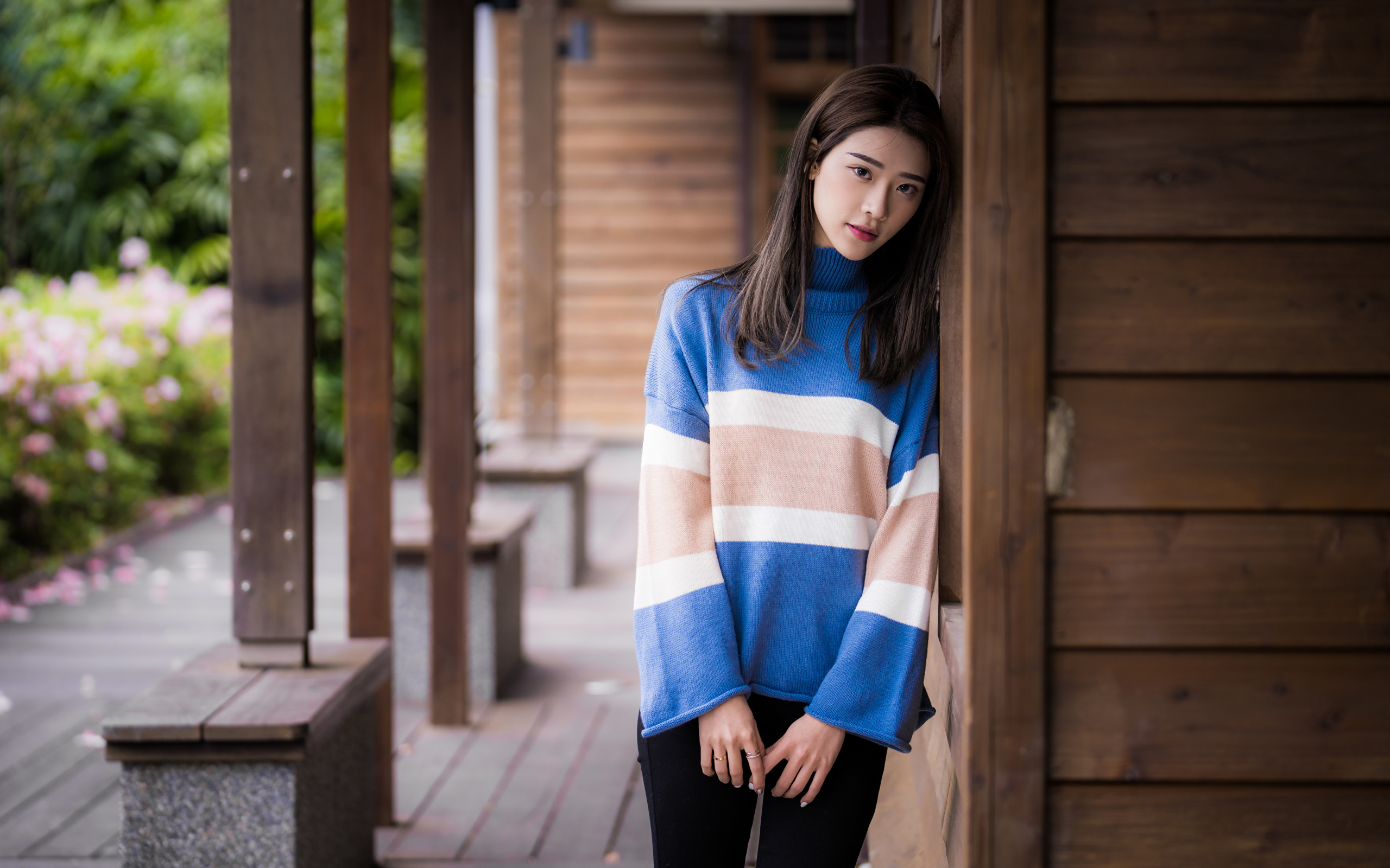 Грустная девушка азиатка в свитере у стены 