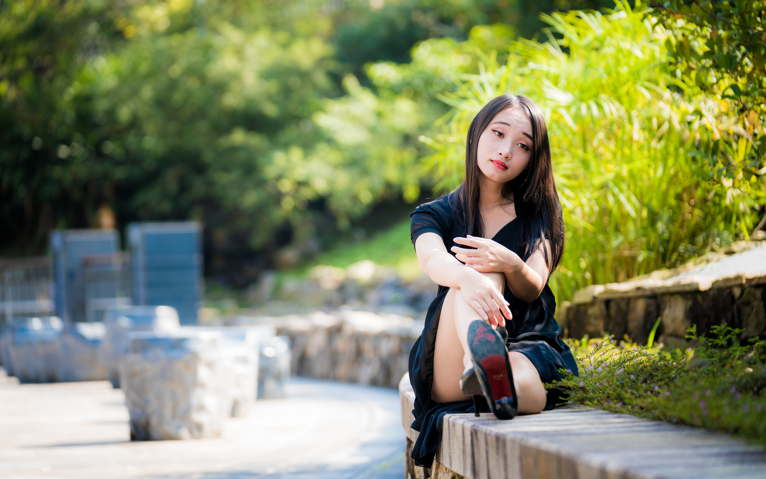 Грустная девушка в черном платье отдыхает в парке