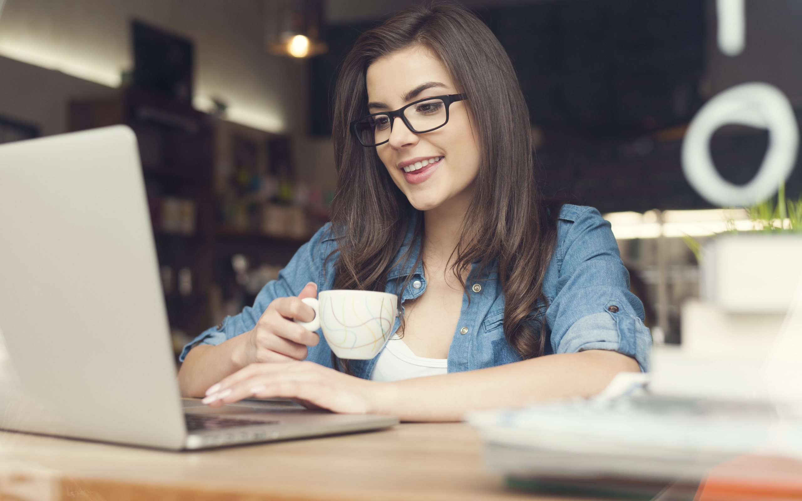 Улыбающаяся девушка в очках с ноутбуком