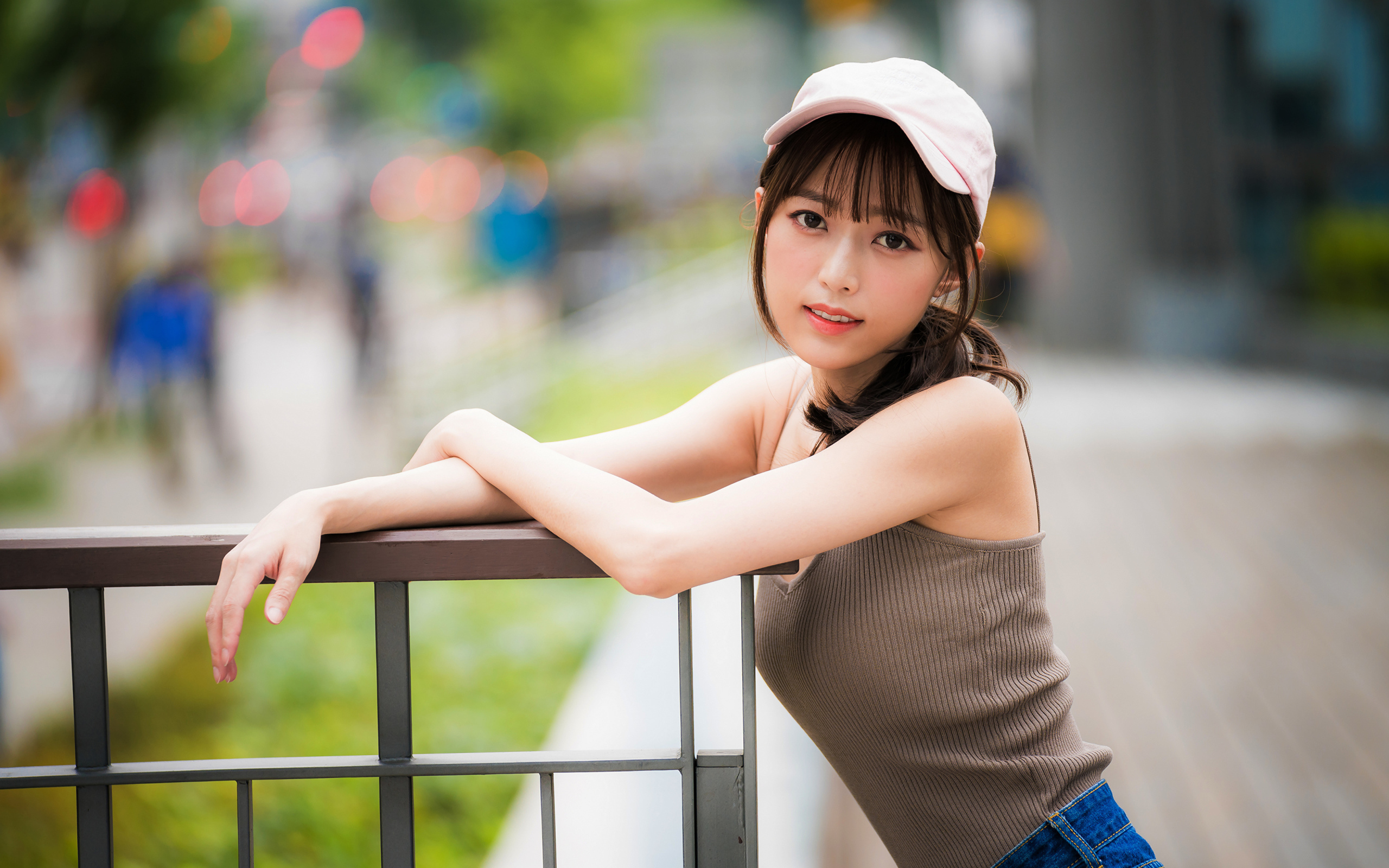 Молодая азиатка в кепке у перил 