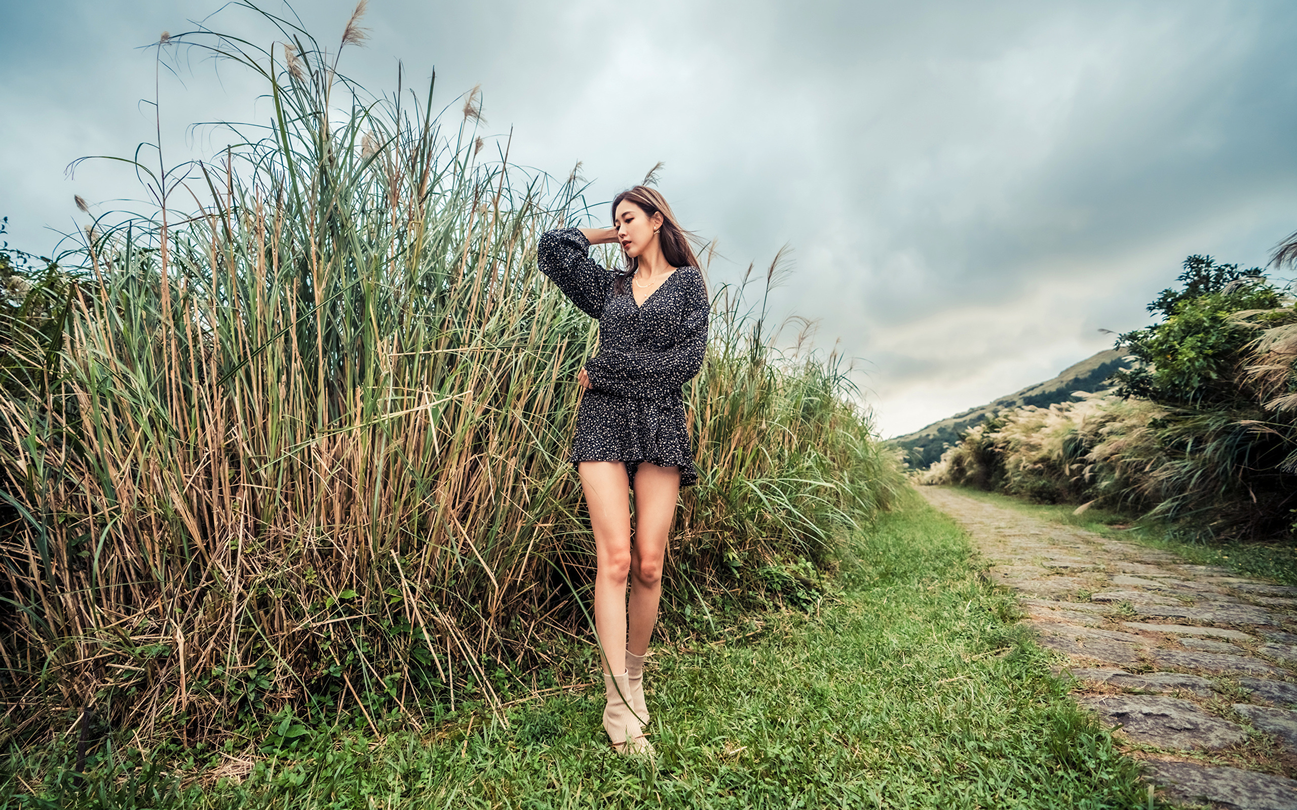 Молодая девушка азиатка стоит у зеленой травы