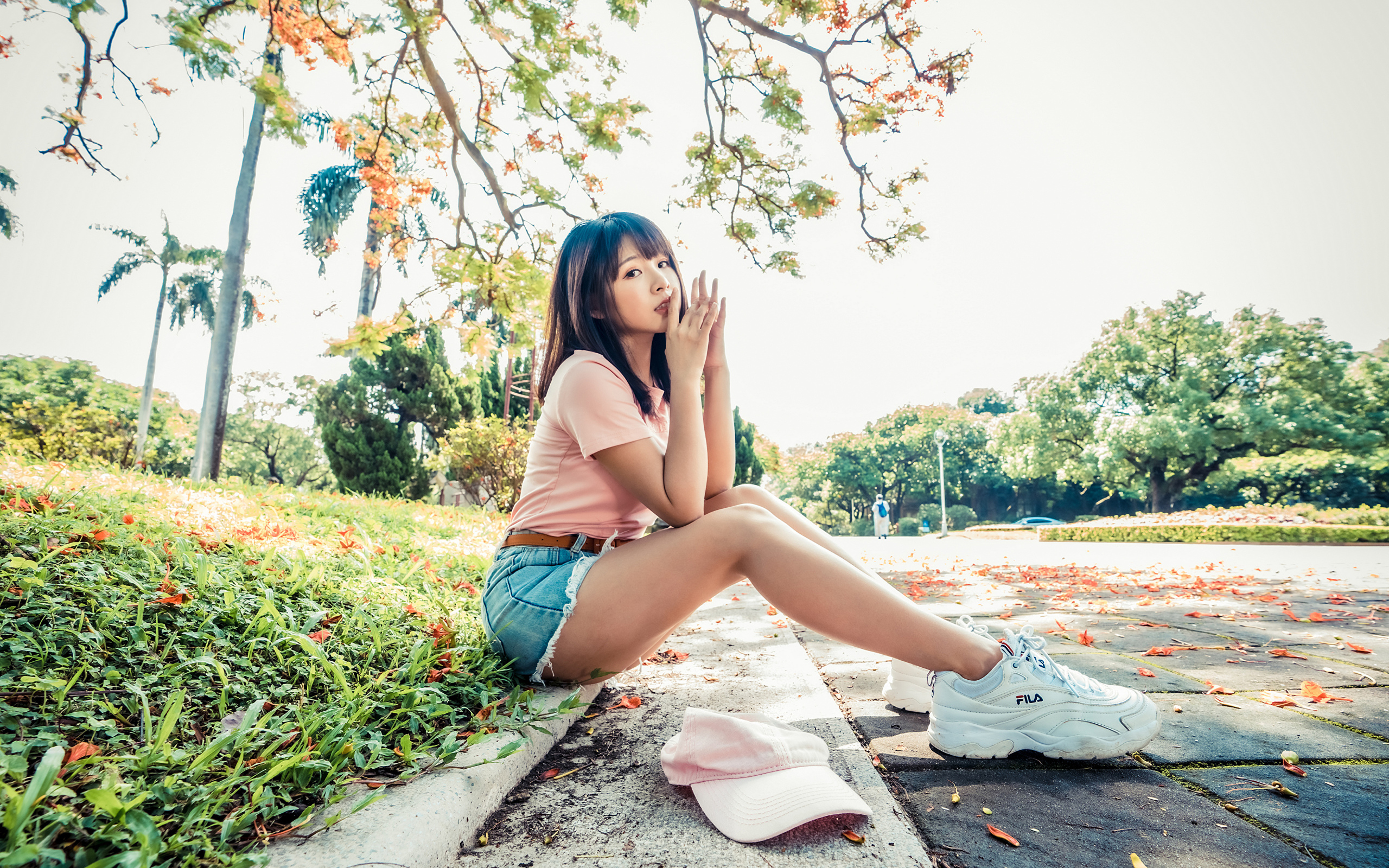 Молодая азиатка сидит на земле в осеннем парке