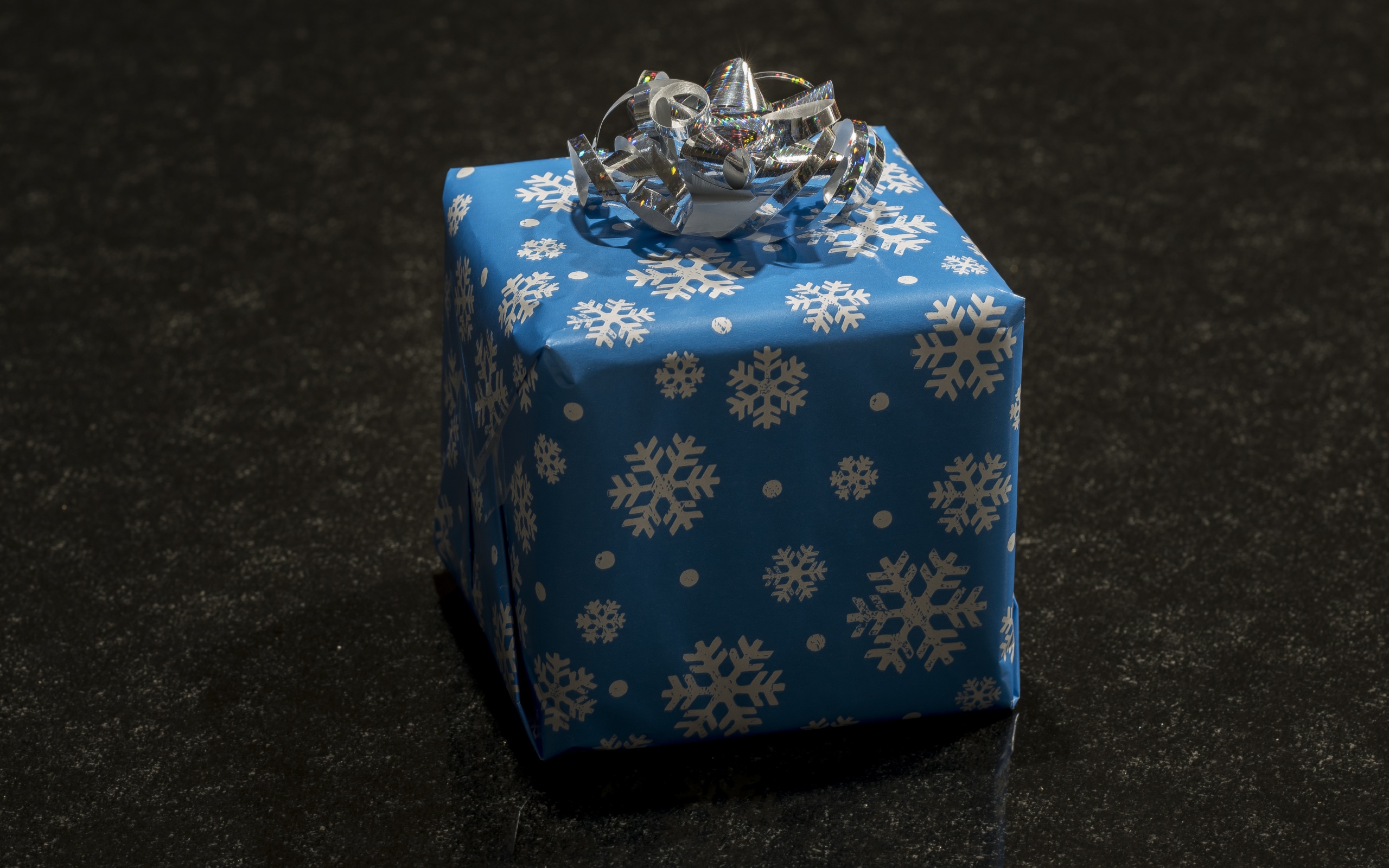 Big blue gift with bow on black background