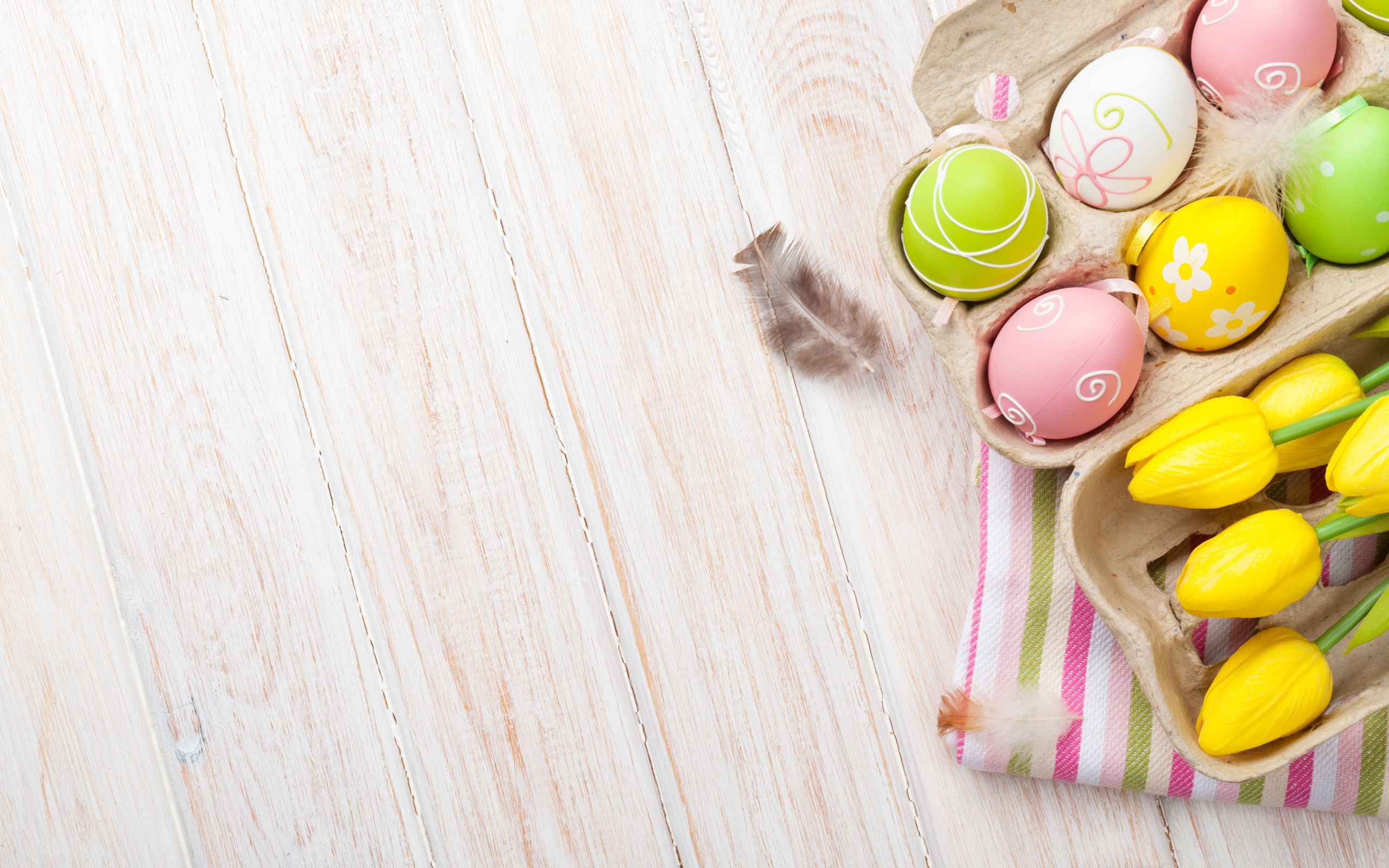 Крашеные пасхальные яйца на столе с тюльпанами