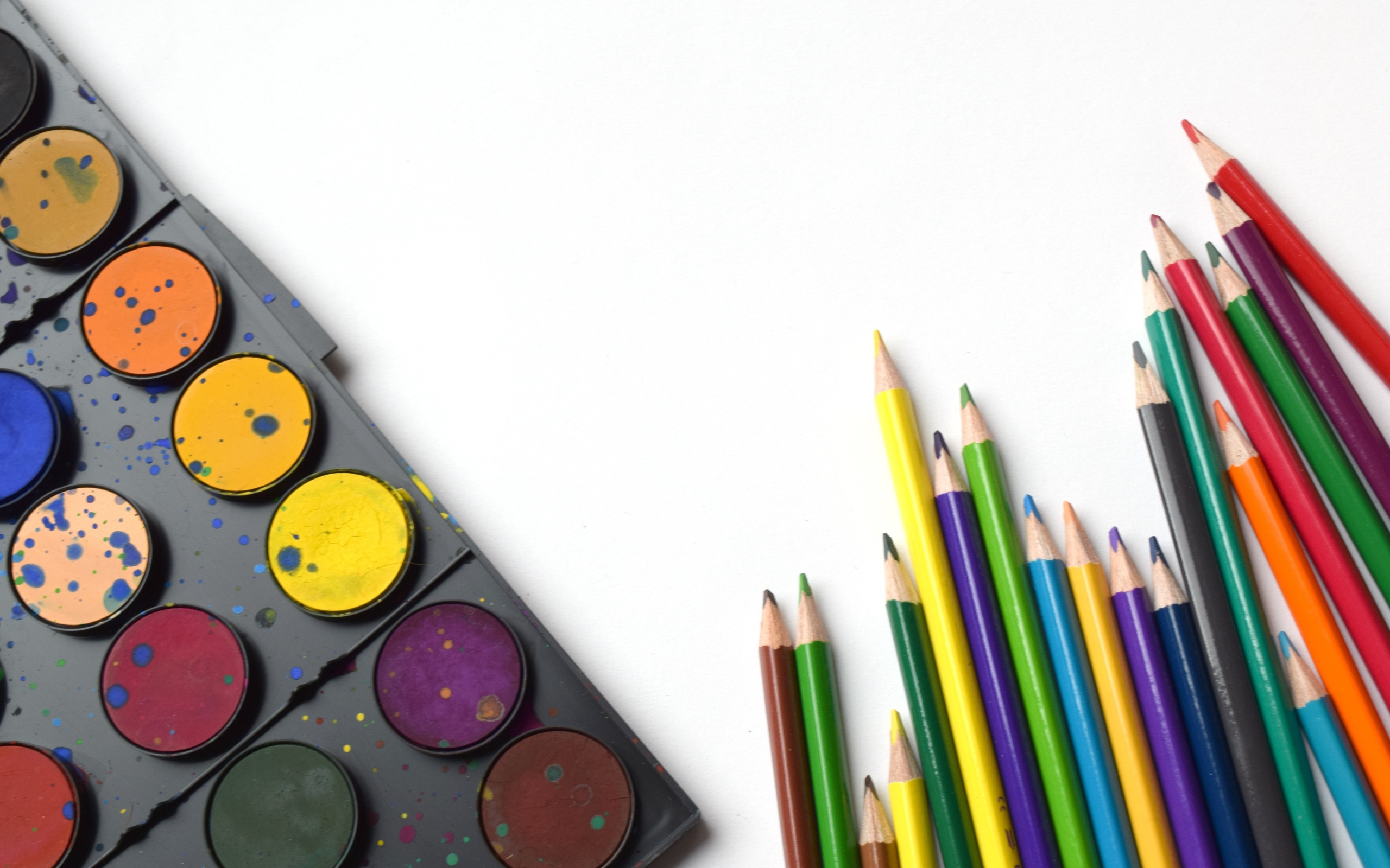 Разноцветные карандаши и краски на белом фоне