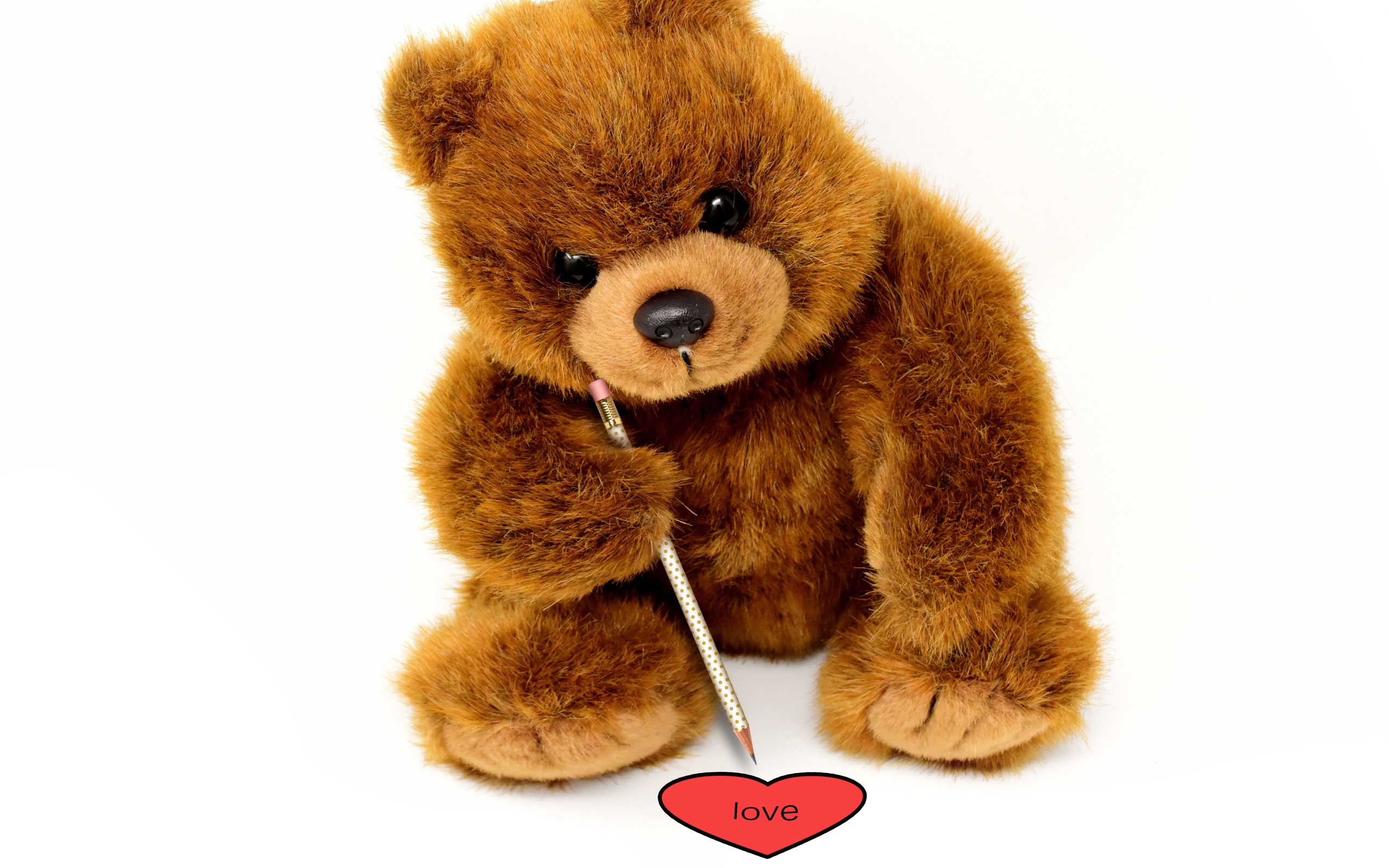 Игрушка медвежонок рисует сердце на белом фоне 