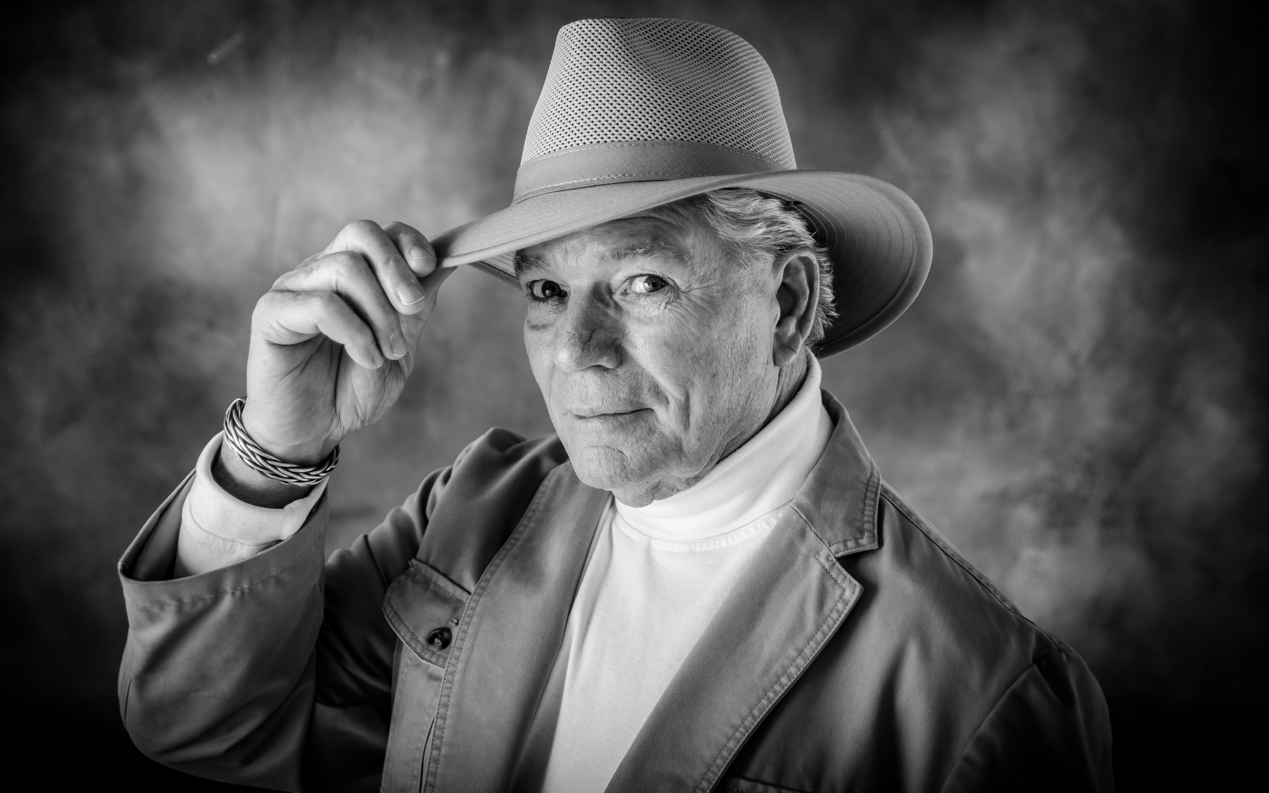 Пожилой мужчина в шляпе на фоне дыма 