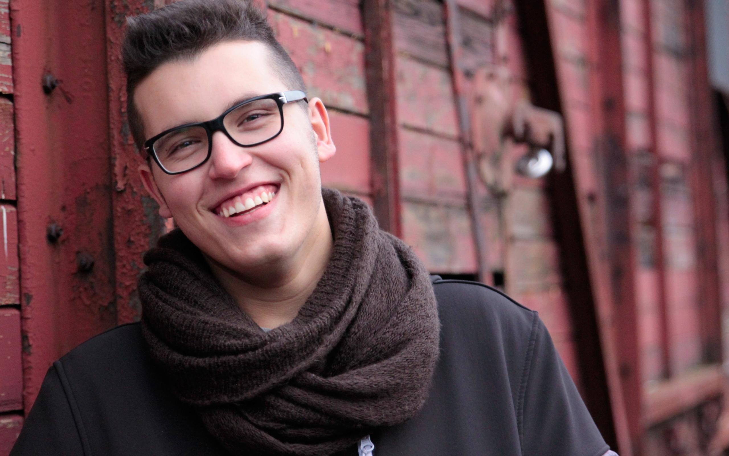 Улыбающийся мужчина в очках у стены 