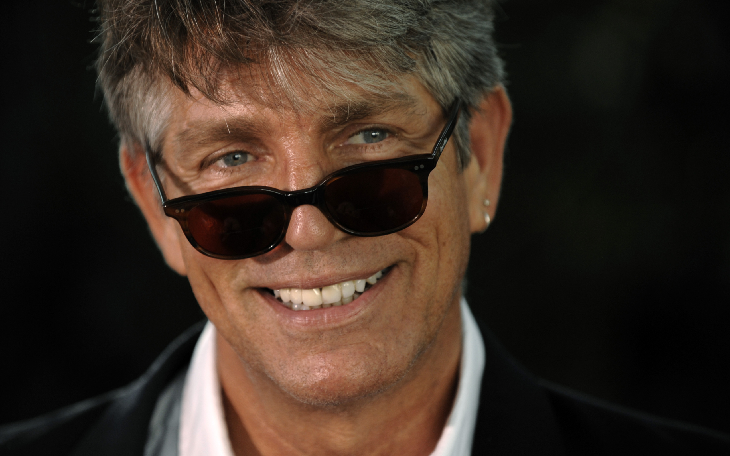 Актер Эрик Робертс в очках на черном фоне