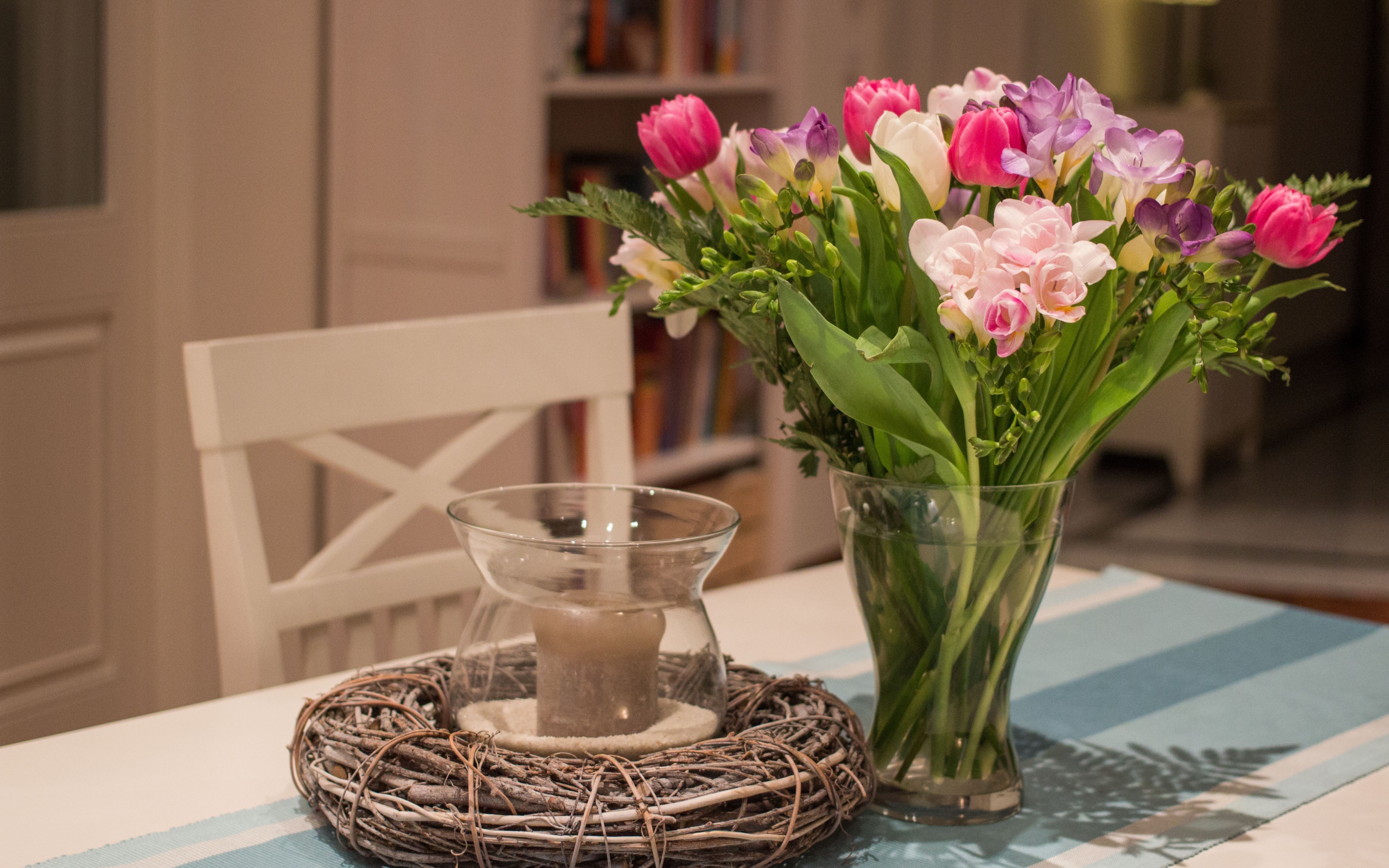 Красивый букет ярких цветов на столе со свечой