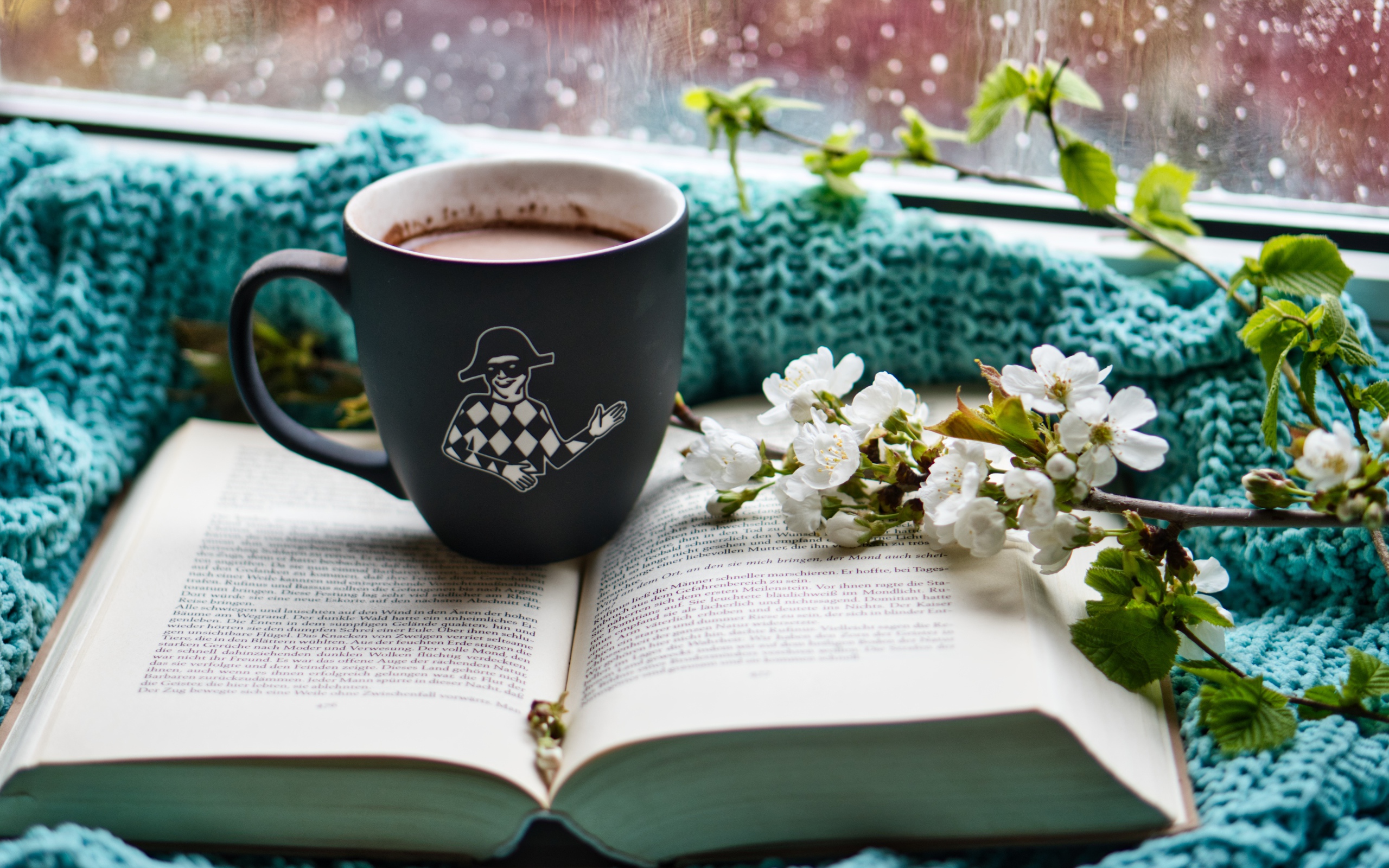 Цветущая ветка вишни на столе с книгой и чашкой кофе