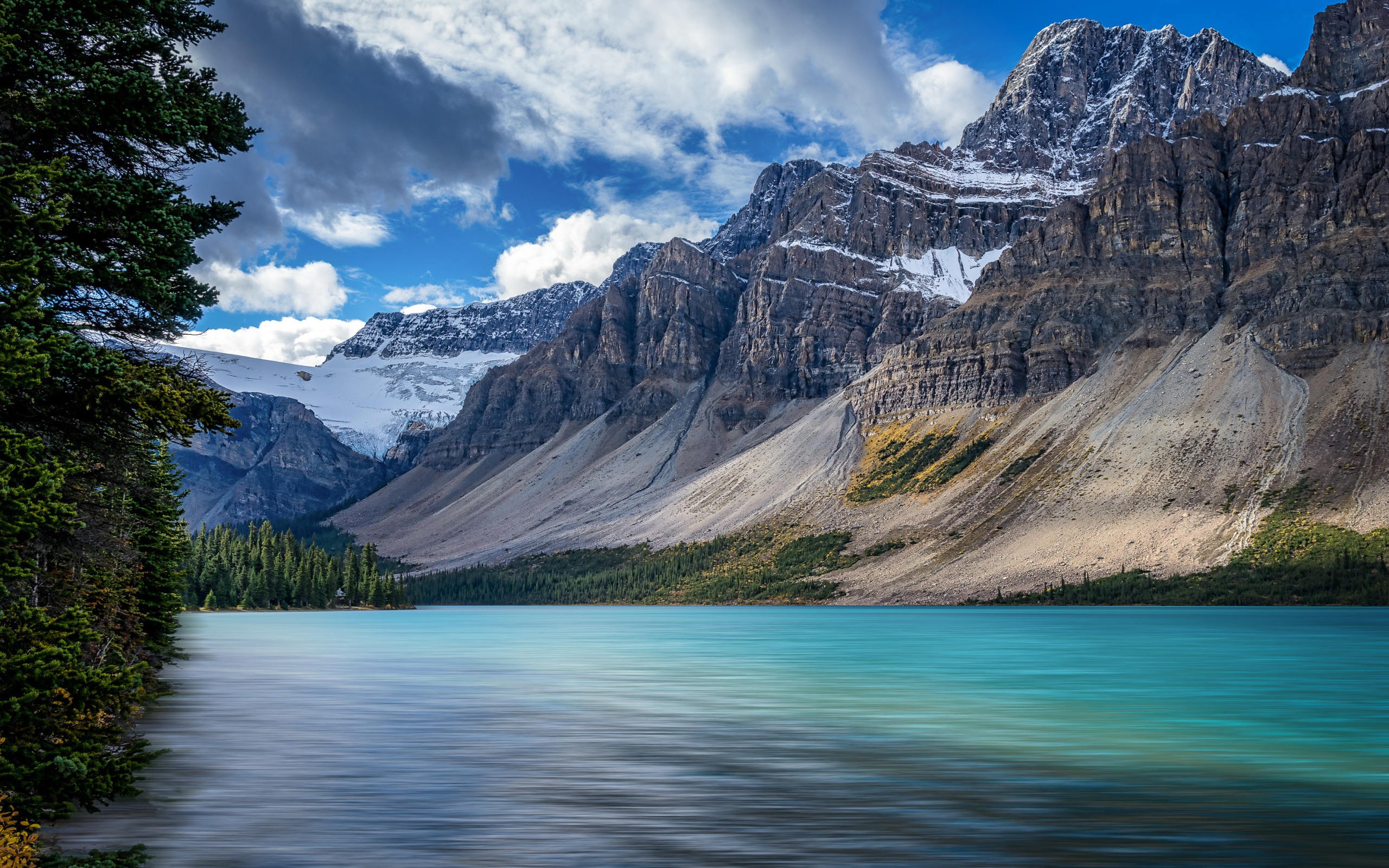Высокие каменные горы в снегу под голубым небом у озера 