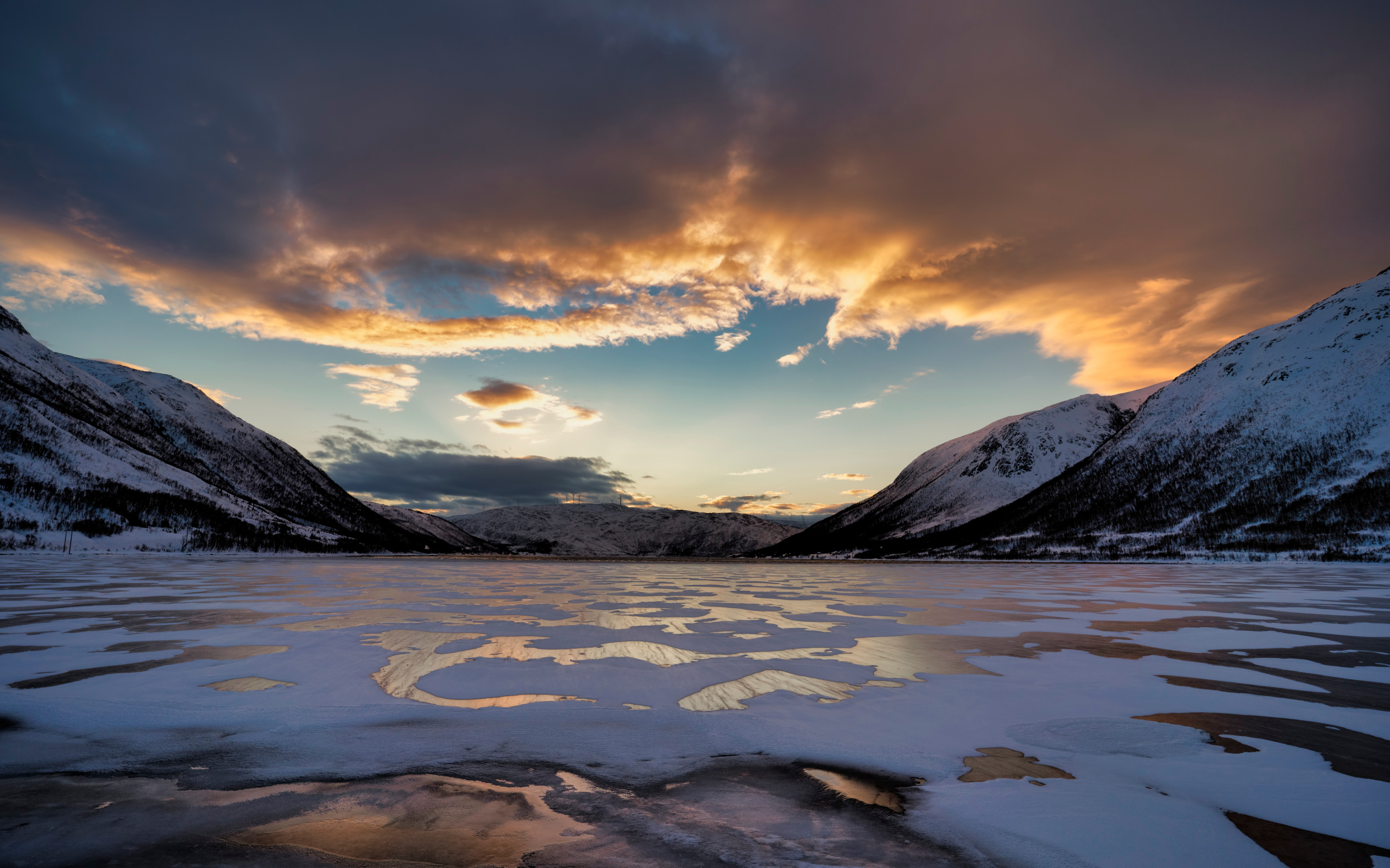 Покрытое льдом озеро у гор на закате солнца 
