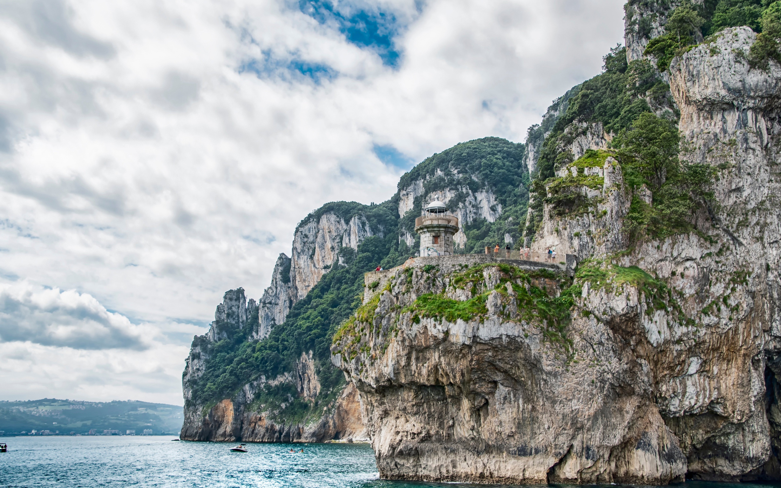 Высокие скалы у моря под белыми облаками 