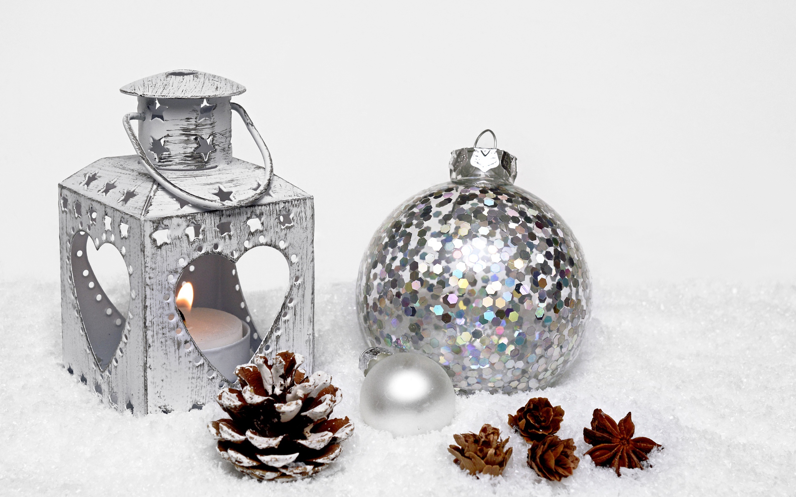 Фонарик и елочный шар с шишками на снегу