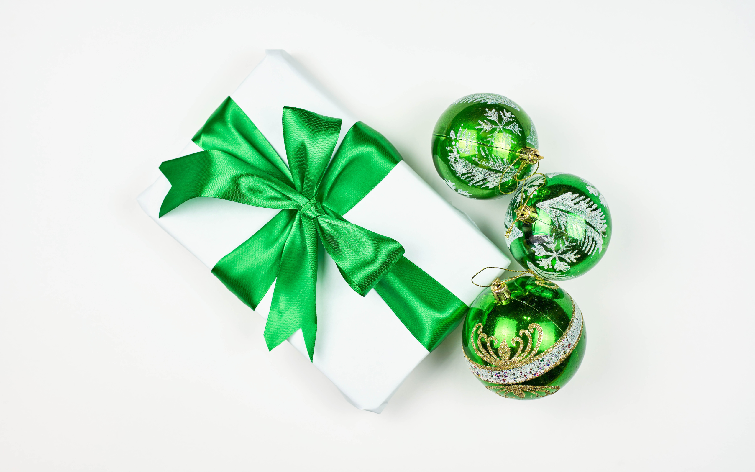 Подарок и три елочных шара на белом фоне 