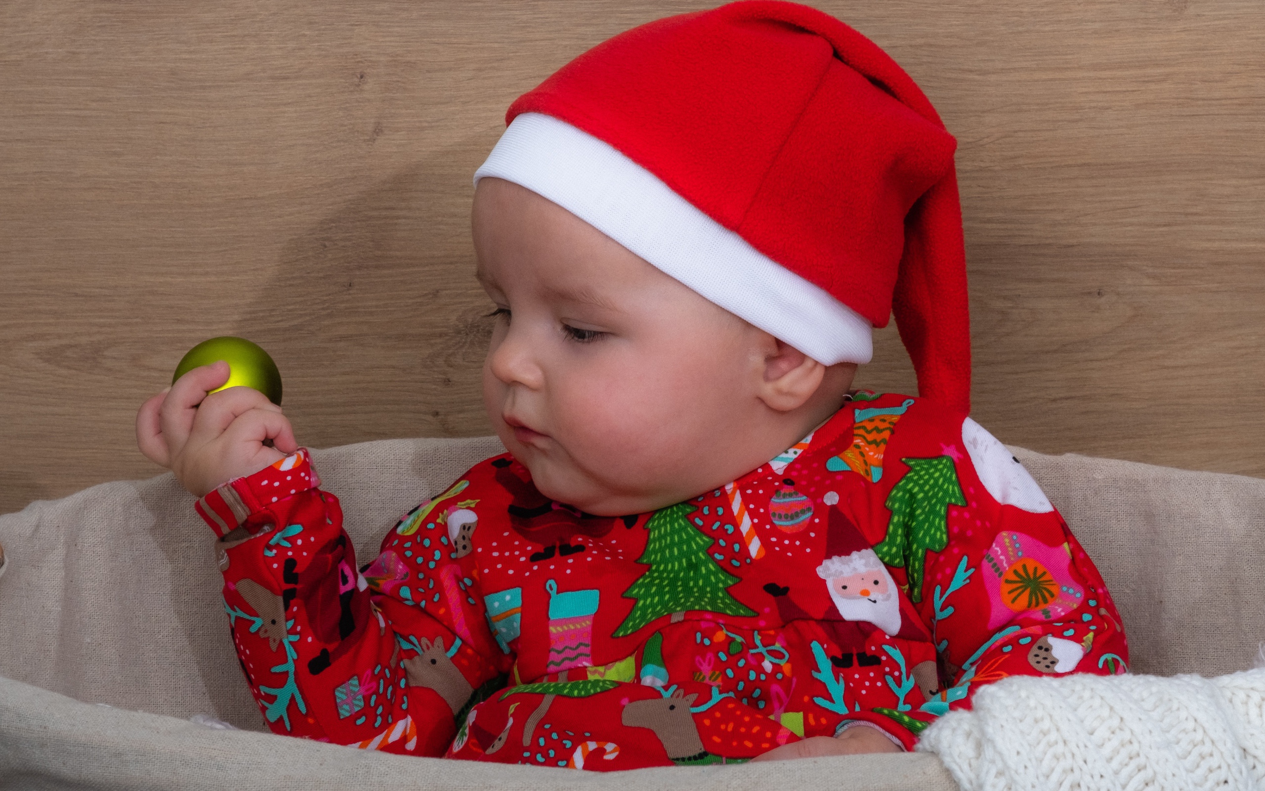 Ребенок в новогодней шапке с игрушкой в руке