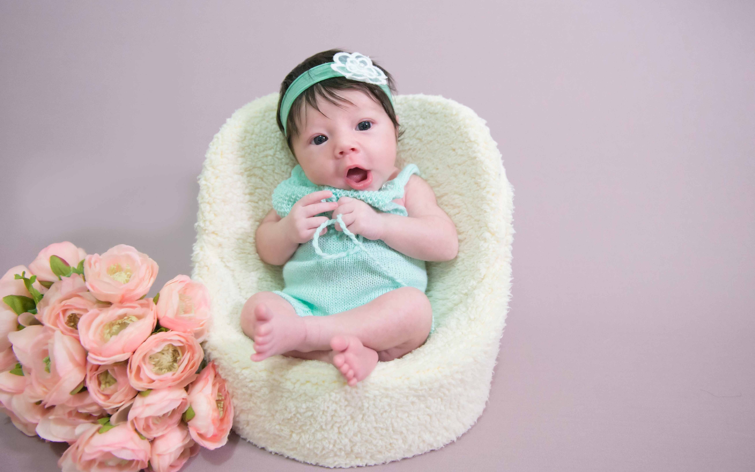 Милая малышка в кресле с букетом цветов