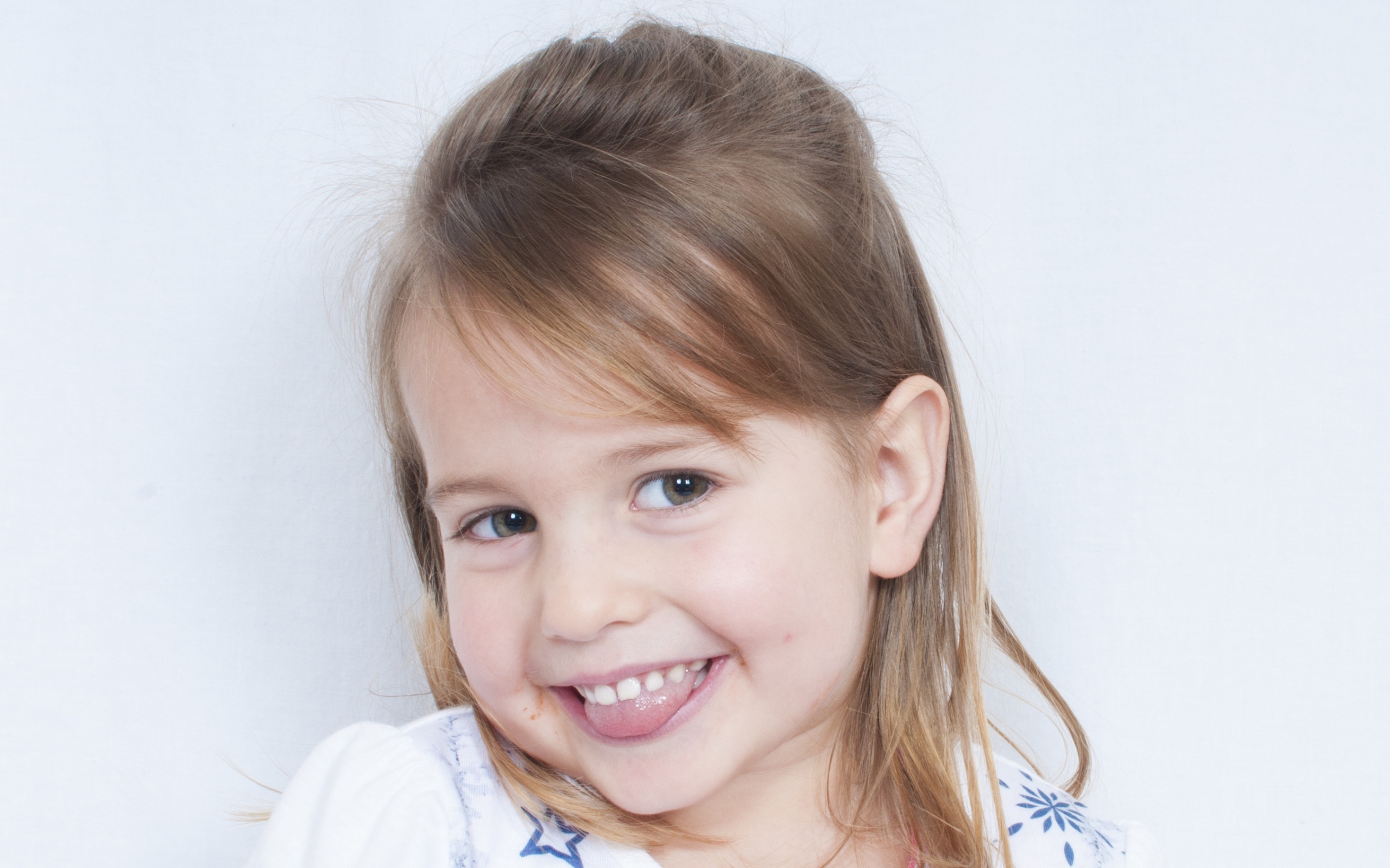 Милая улыбающаяся девочка с высунутым языком