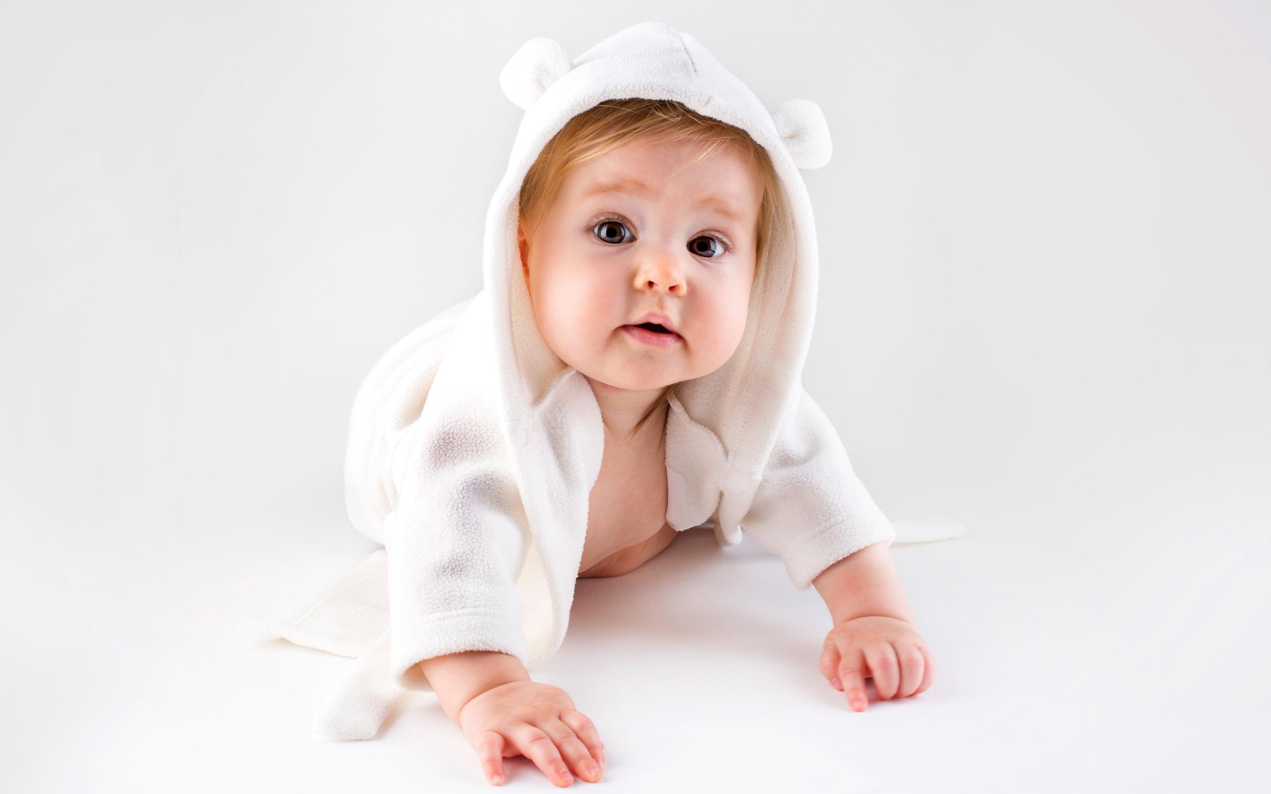 Забавный малыш ползает в белом наряде 