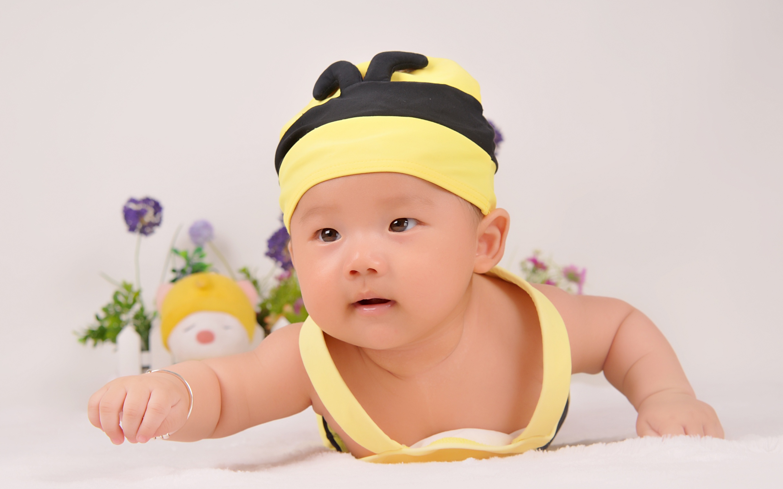 Маленький мальчик в шапке пчелы на сером фоне 