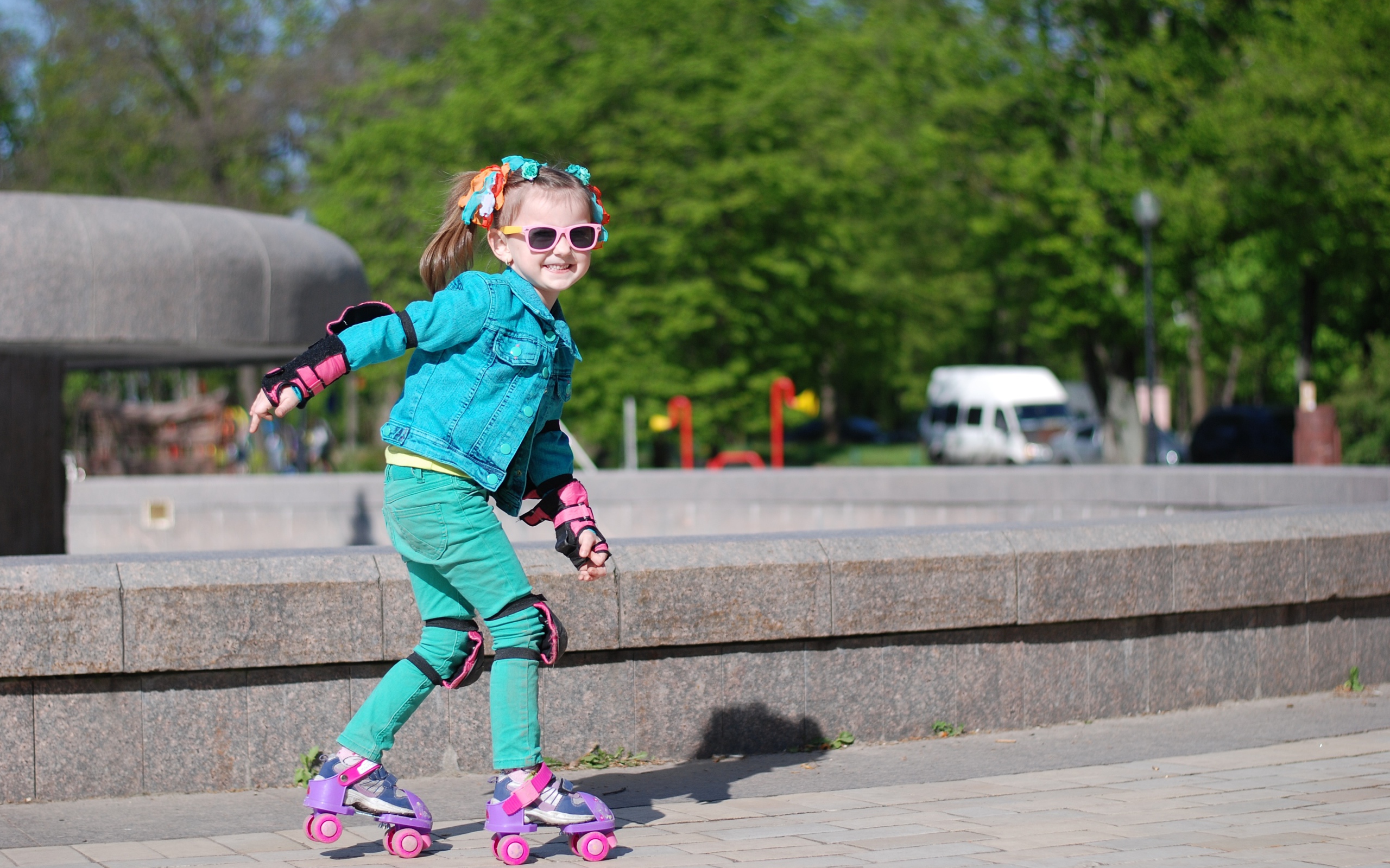 Маленькая веселая девочка катается на роликах