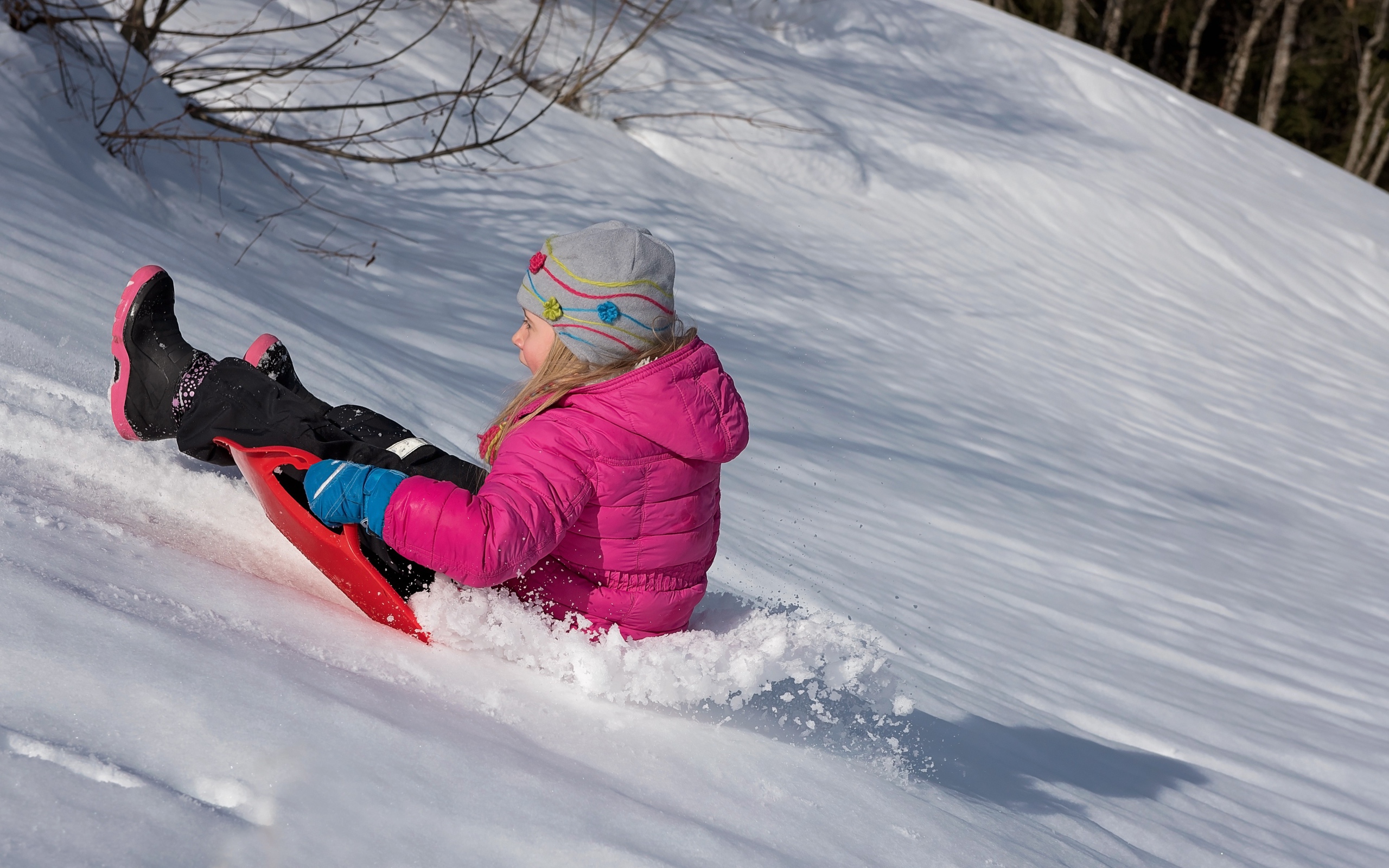 Маленькая девочка катится с заснеженной горки 