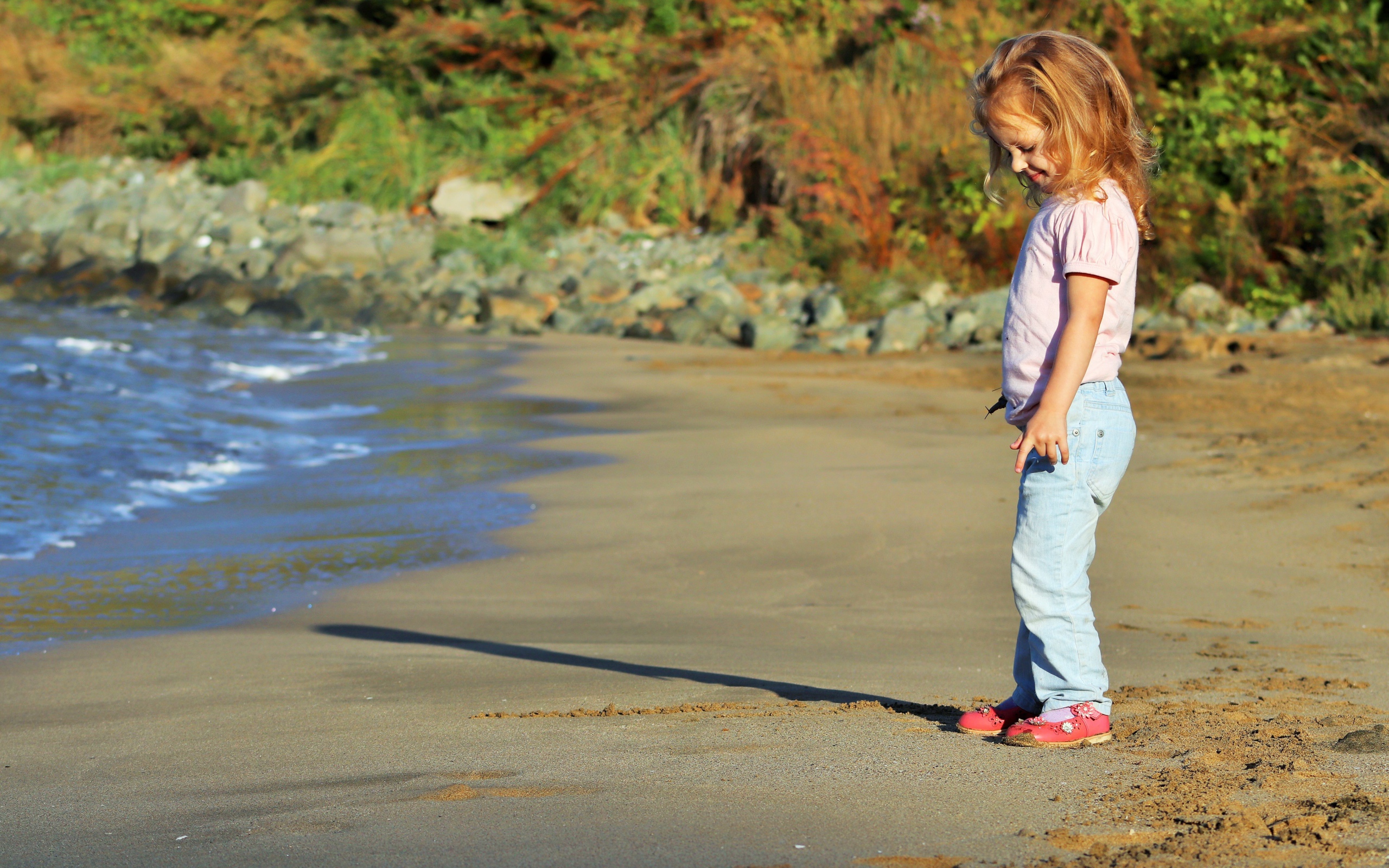 Маленькая девочка гуляет по мокрому песку 